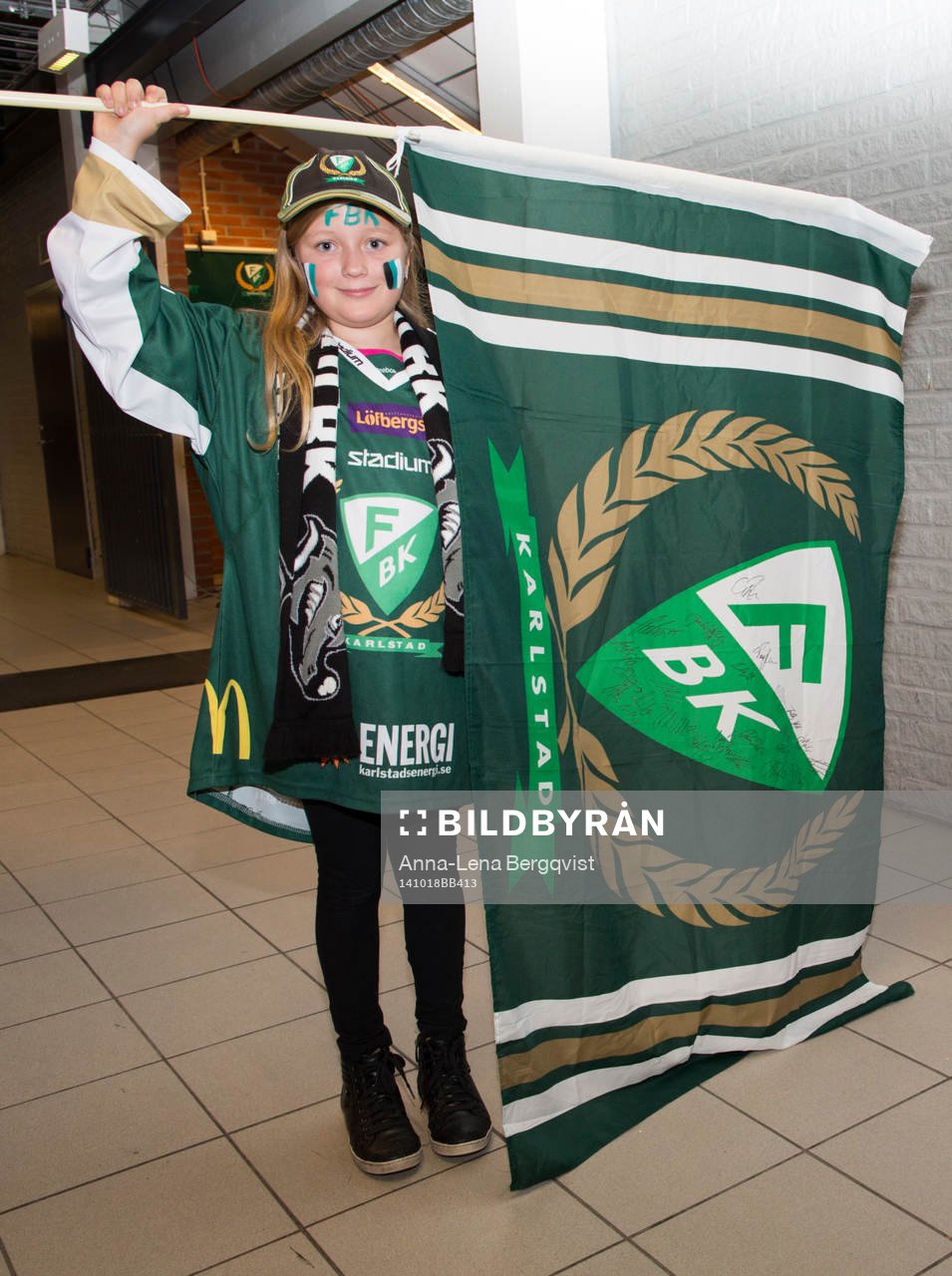 En ung Färjestadssupporter med ansiktsmålning och flagga