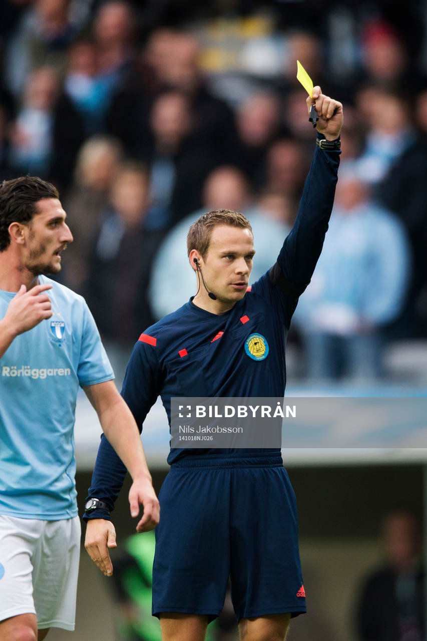 Domare Kristoffer Karlsson ger ett gult kort under den allsvenska fotbollsmatchen mellan Malmö FF och Elfsborg den 18 oktober 2014 i Malmö.