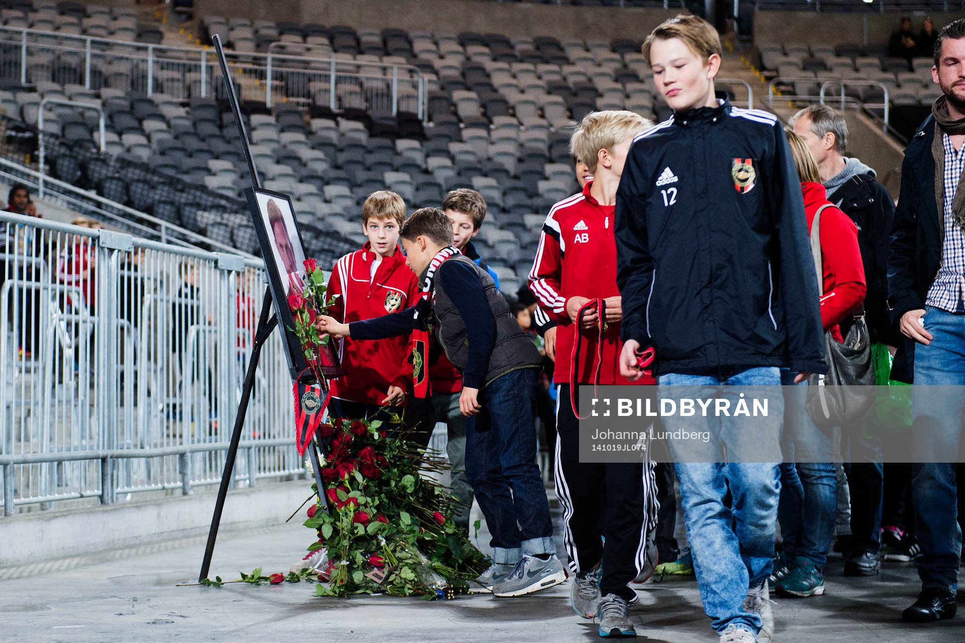 Besökare lägger ut rosor vid ett porträtt av Pontus Segerström under fotbollsmatchen i Allsvenskan mellan Brommapojkarna och AIK den 19 oktober 2014 i Stockholm.