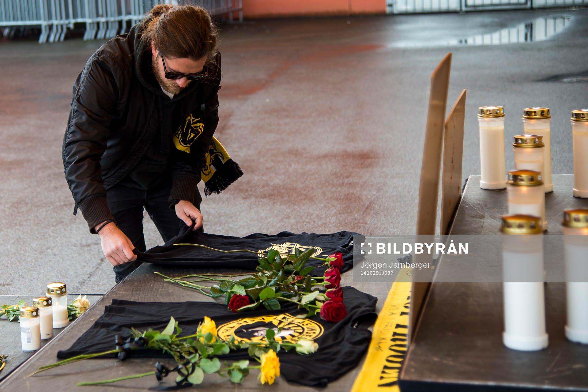 Supporter lägger ner en röd ros och tröja från