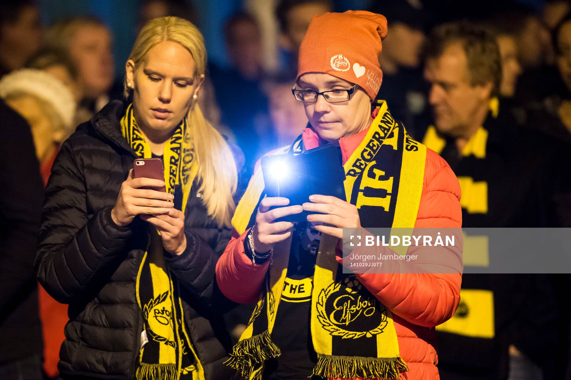 Sörjande supportrar fotograferar med mobiltelefoner