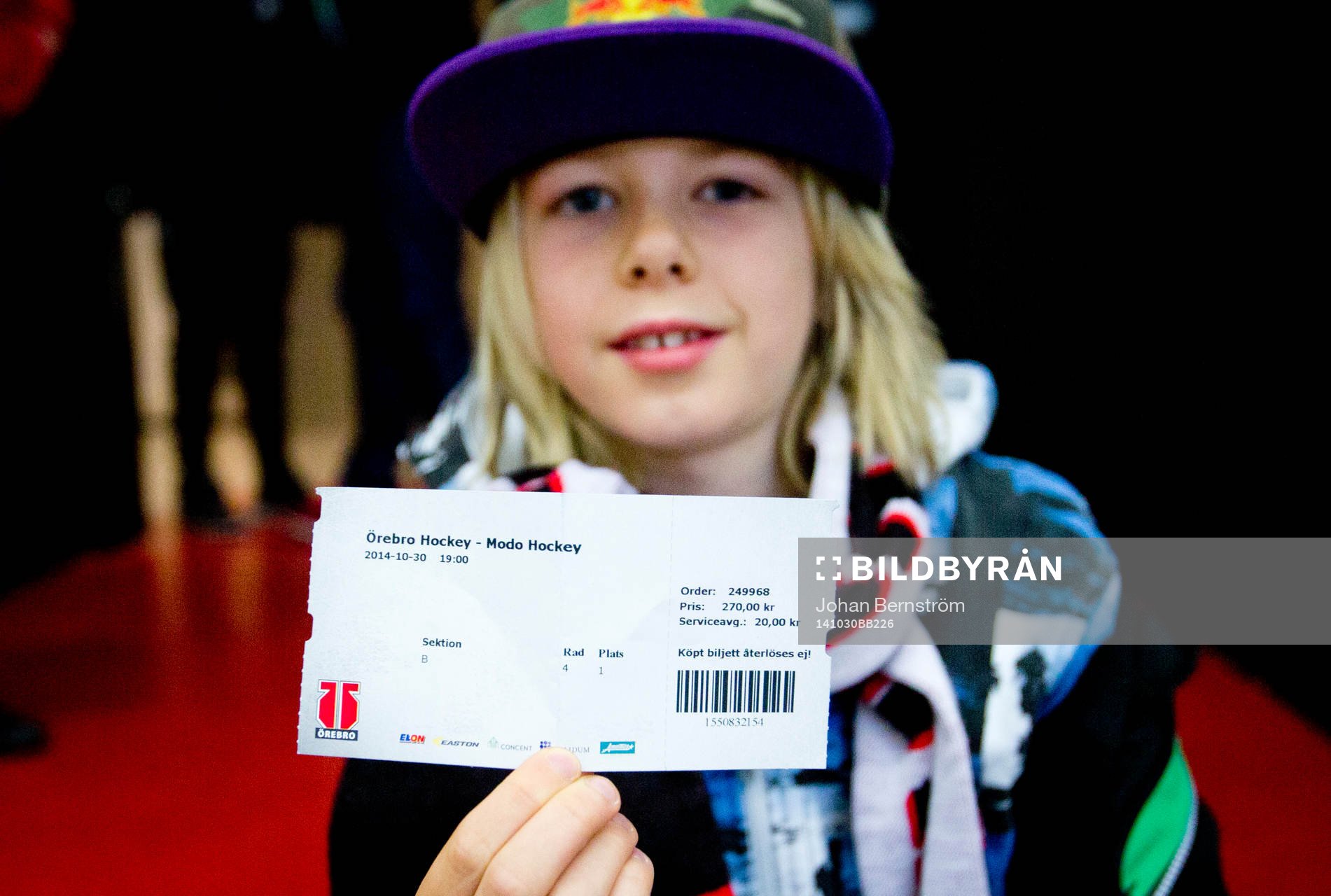 En ung supporter håller upp matchbiljetten