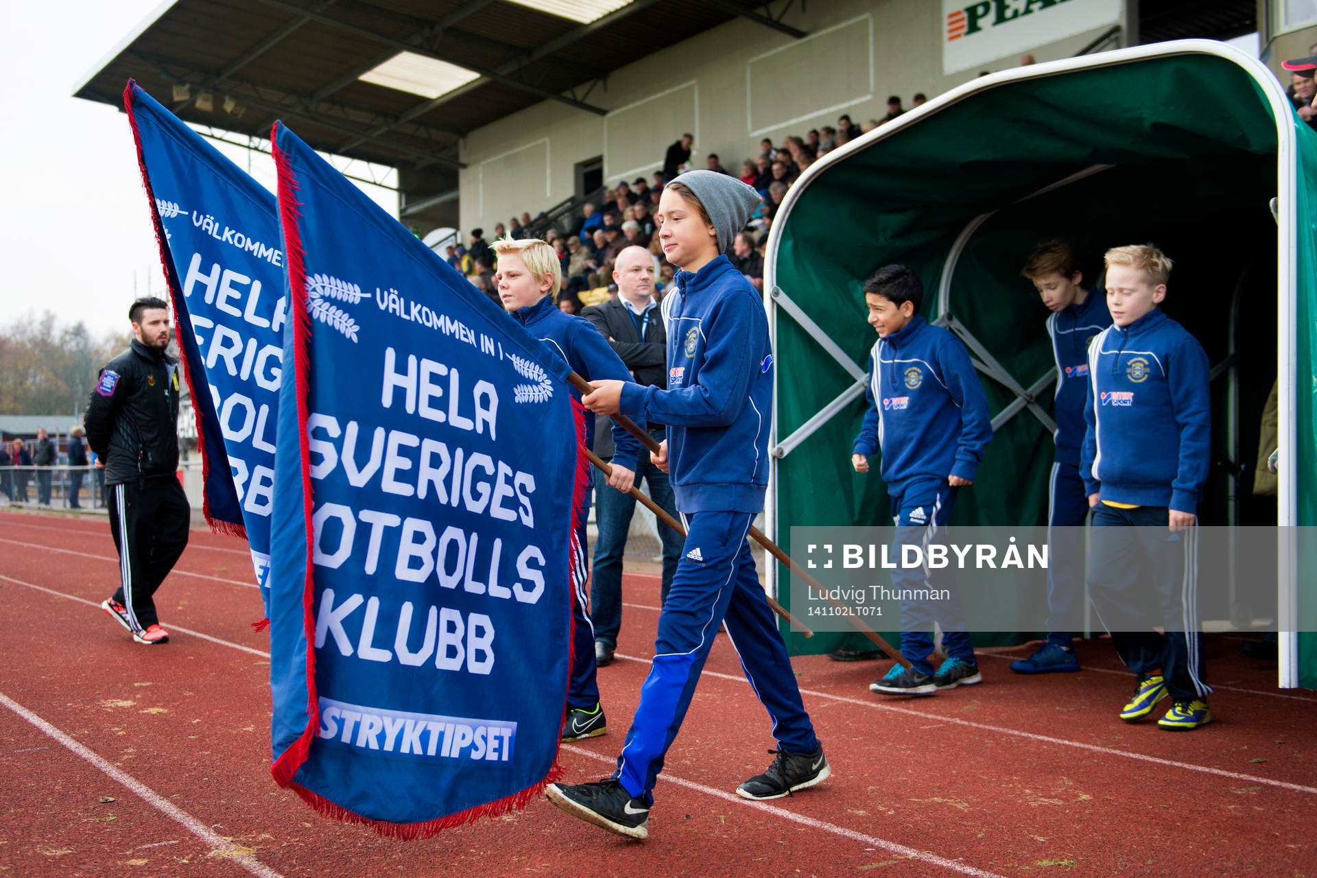 Bollkallarna går in med flaggor Hela Sveriges Fotbollsklubb från Stryktipset och Svenska spel införfotbollsmatchen i Superettan mellan Ängelholm och Östersund den 2 november 2014 i Ängelholm.