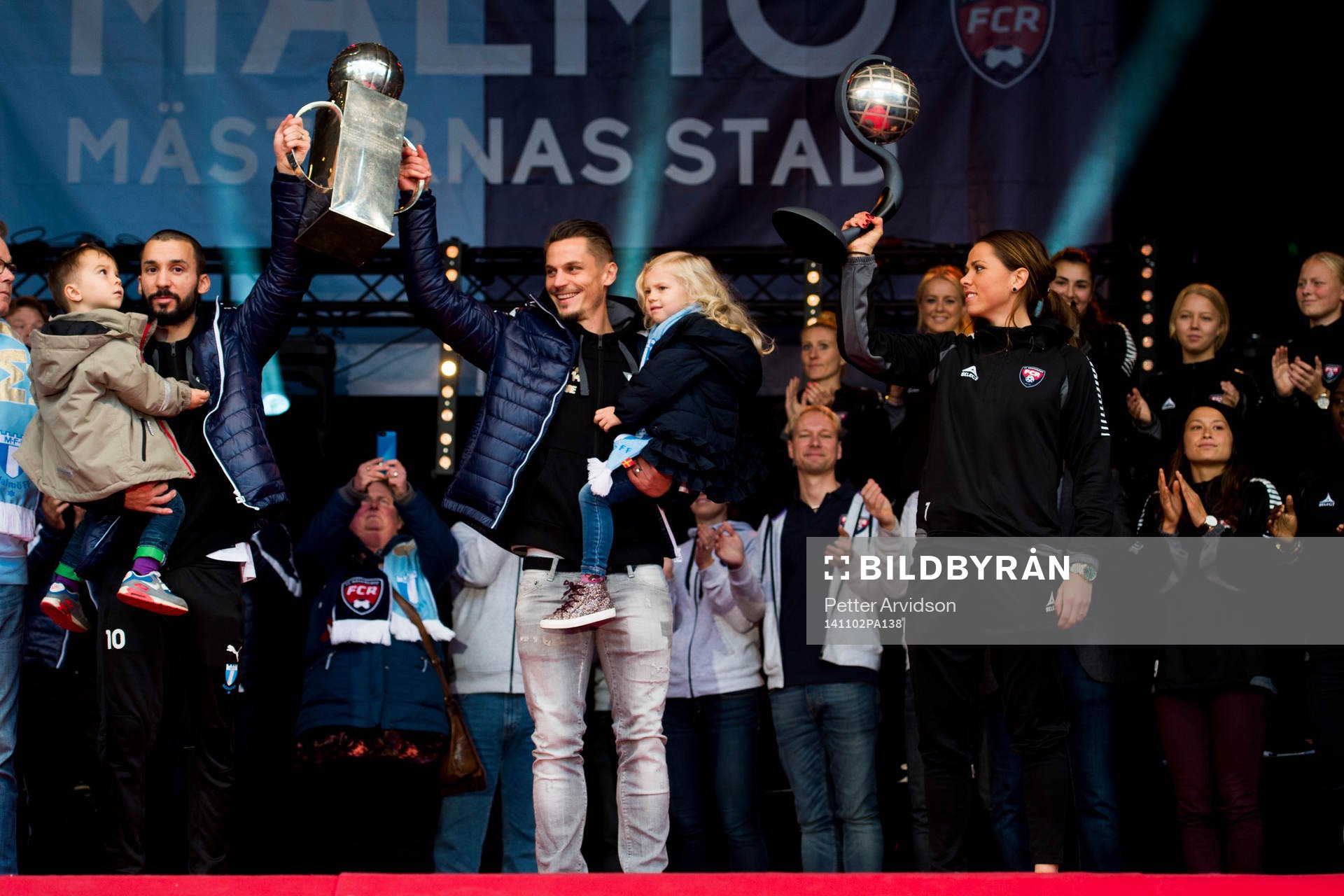Malmö FFs Guillermo Molins och Markus Rosenberg höjer Lennart Johanssons Pokal och Rosengårds Sara Björk Gunnarsdottir höjer Kronprinsessan Victorias pokal när Malmö FF och Rosengård hyllas föra sina SM-guld den 2 november 2014 på Stortorget i Malmö.