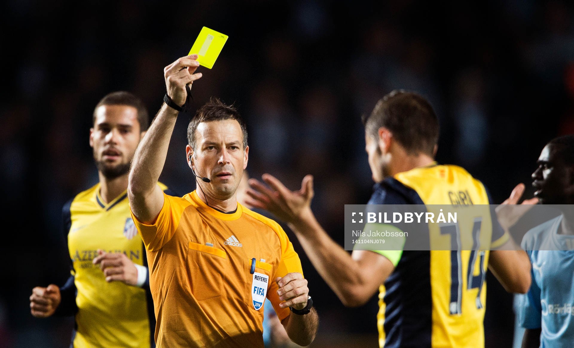 domare Mark Clattenburg ger gult kort till Atletico Madrids