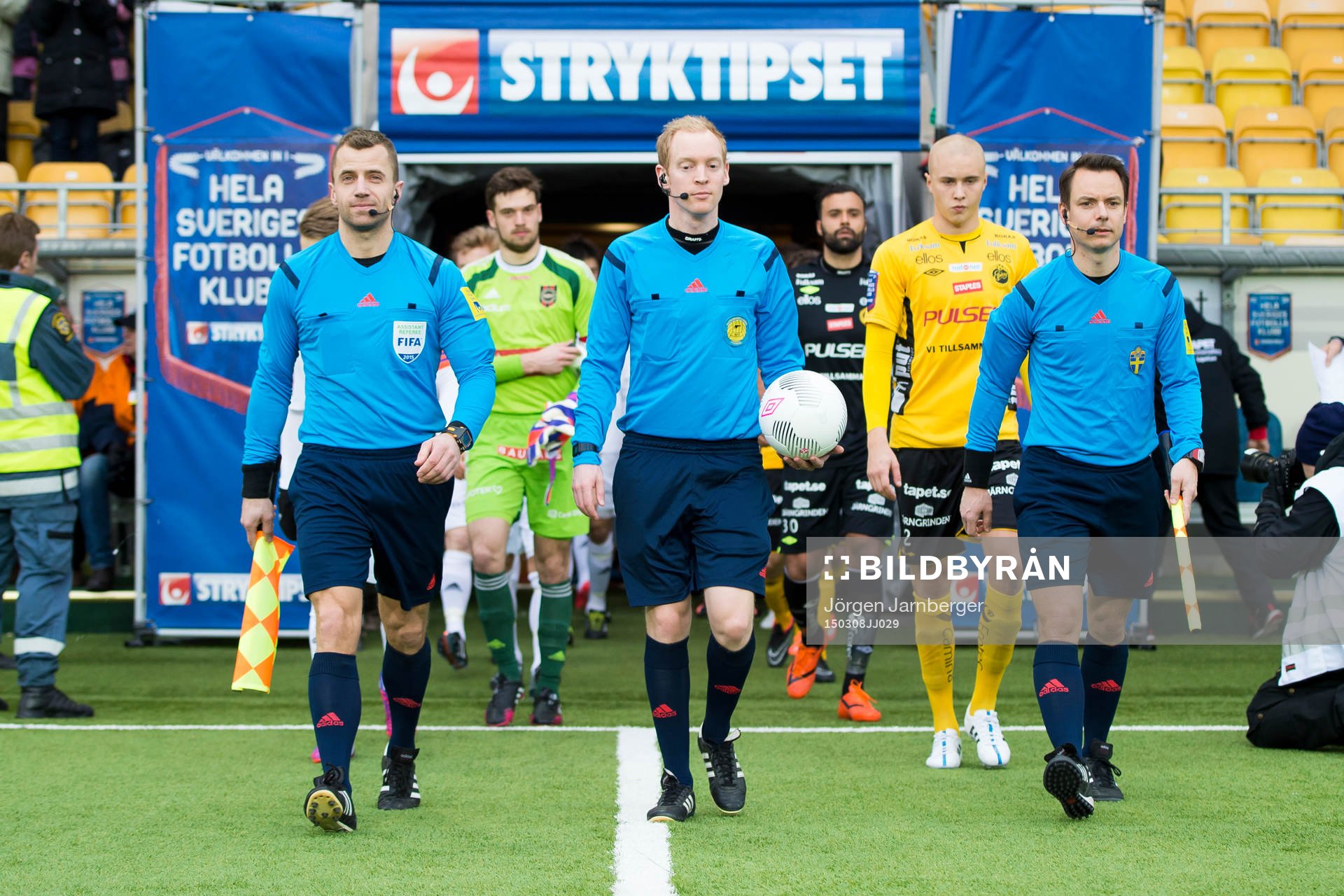Domare och spelare på inmarsch innan fotbollsmatchen i