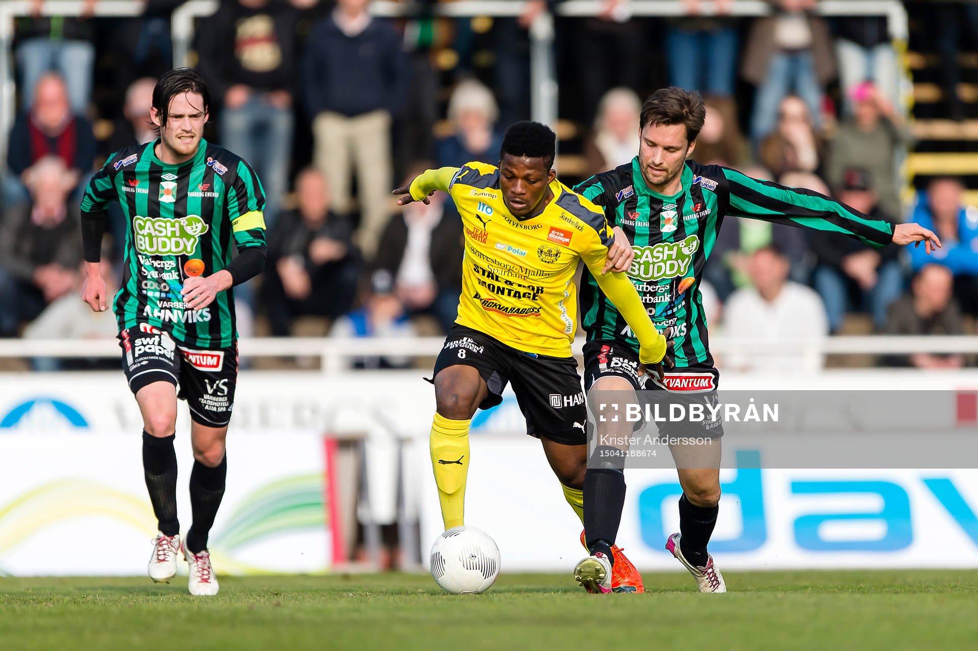 Mjällbys Benjamin Fadi i kamp med Varbergs Peter Nyström under fotbollsmatchen i Superettan mellan Varberg och Mjällby den 11 april 2015 i Varberg.