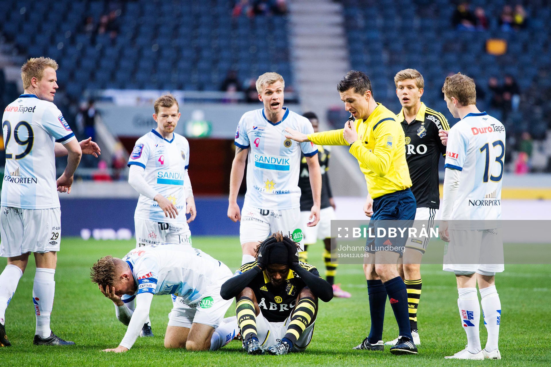 AIK:s Mohamed Bangura tar sig för huvudet medans Gefles Robin Nilsson reagerar mot domare Bojan Pandzic under fotbollsmatchen i Allsvenskan mellan AIK och Gefle den 12 april 2015 i Stockholm.