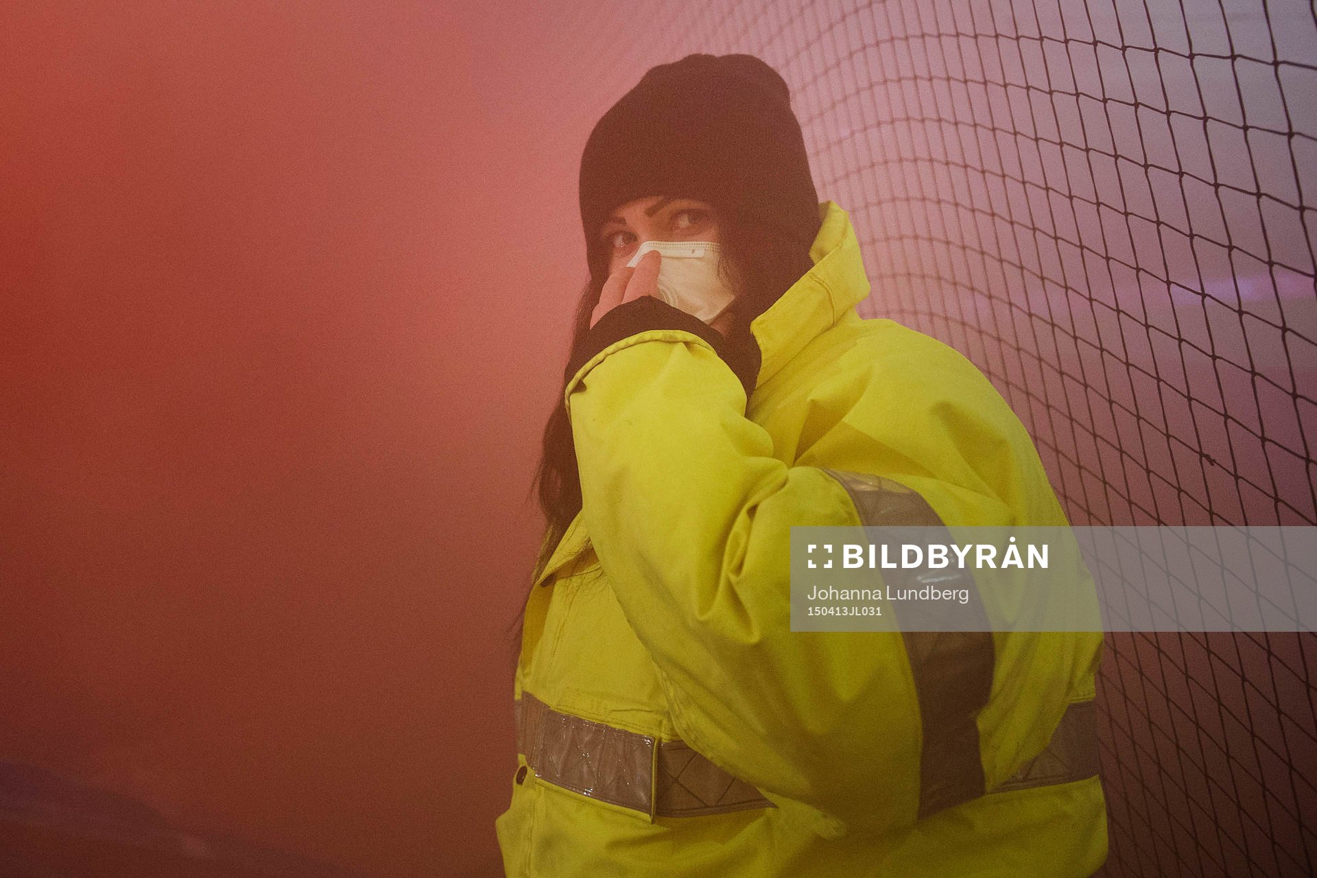 En publikvärd med mask för att komma undan röken