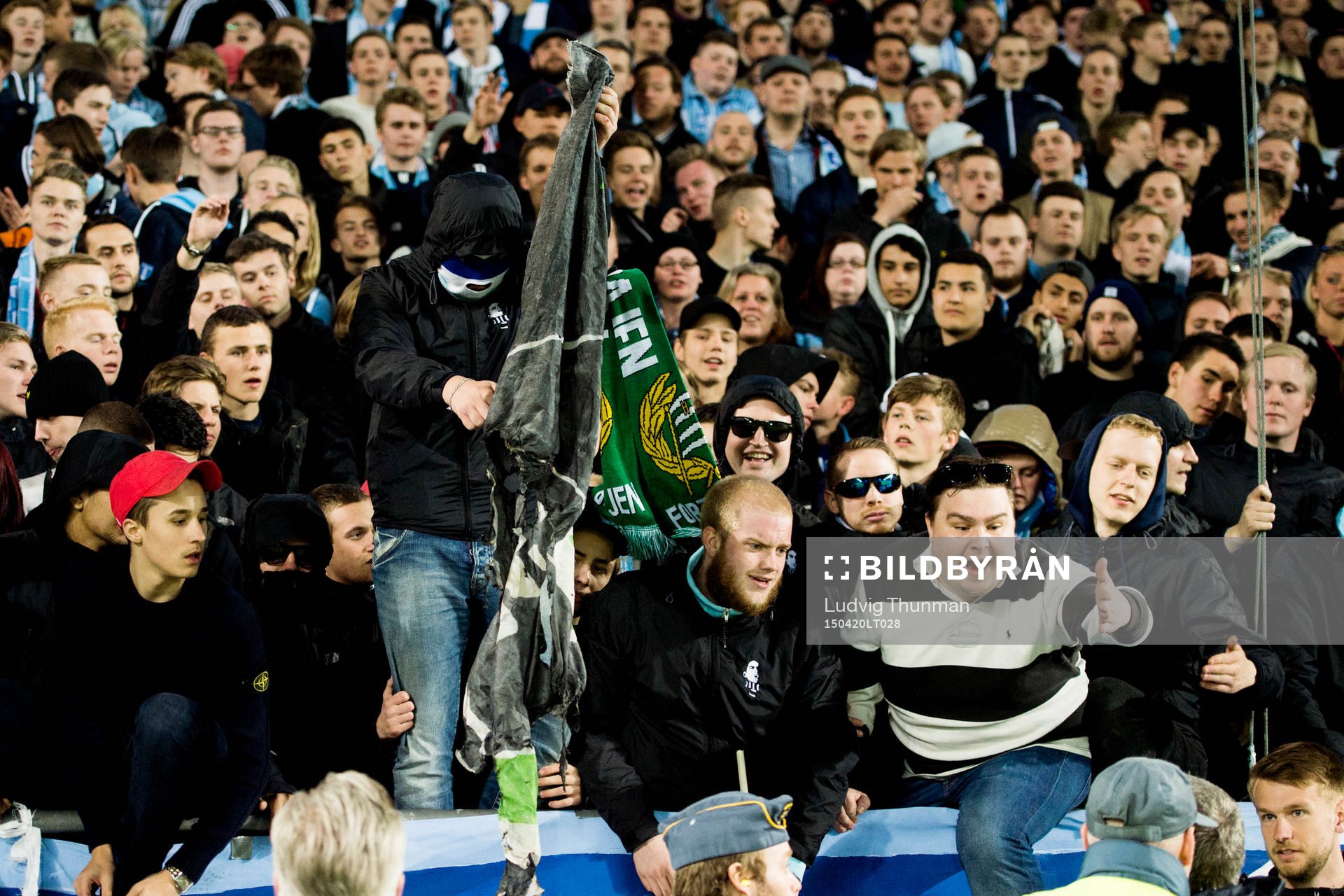 En maskerad malmösupporter bränner en Hammarbys flagga