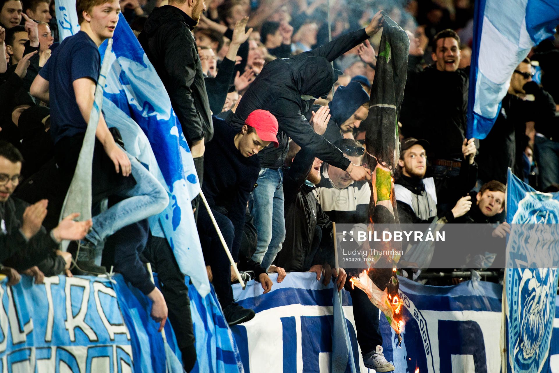 En maskerad malmösupporter bränner en Hammarbys flagga