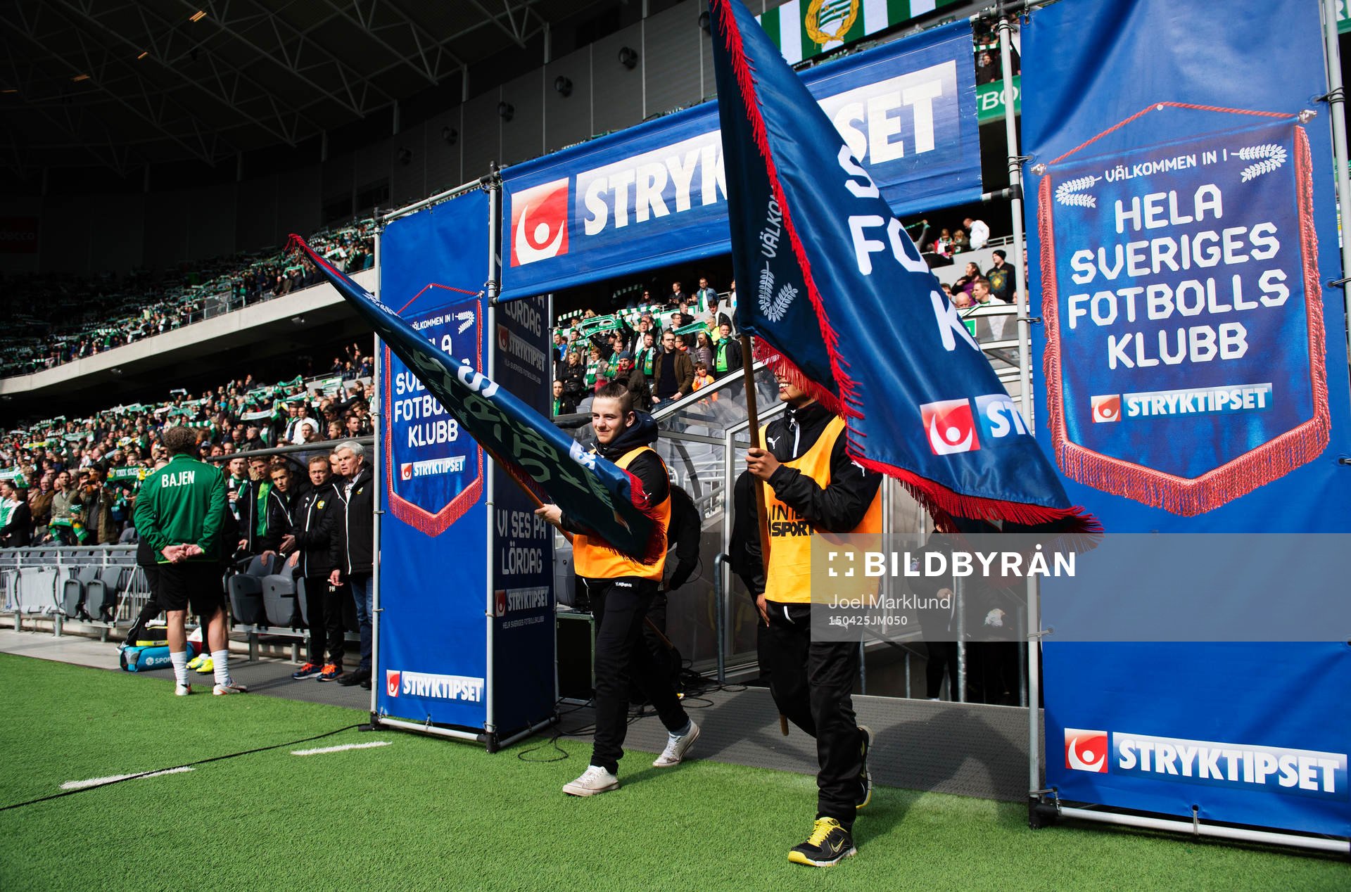 Ungdomar med fanor gör entré till fotbollsmatchen i