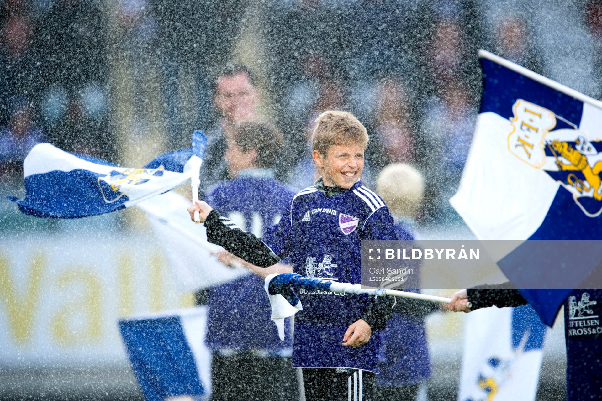 En kille viftar med en flagga innan en fotbollsmatch i