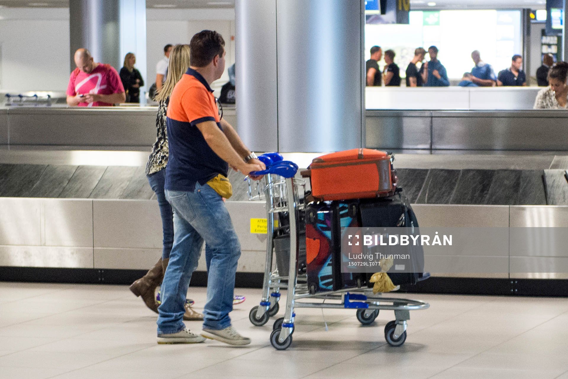 En man och en kvinna kör en bagagevagn på en flygplats