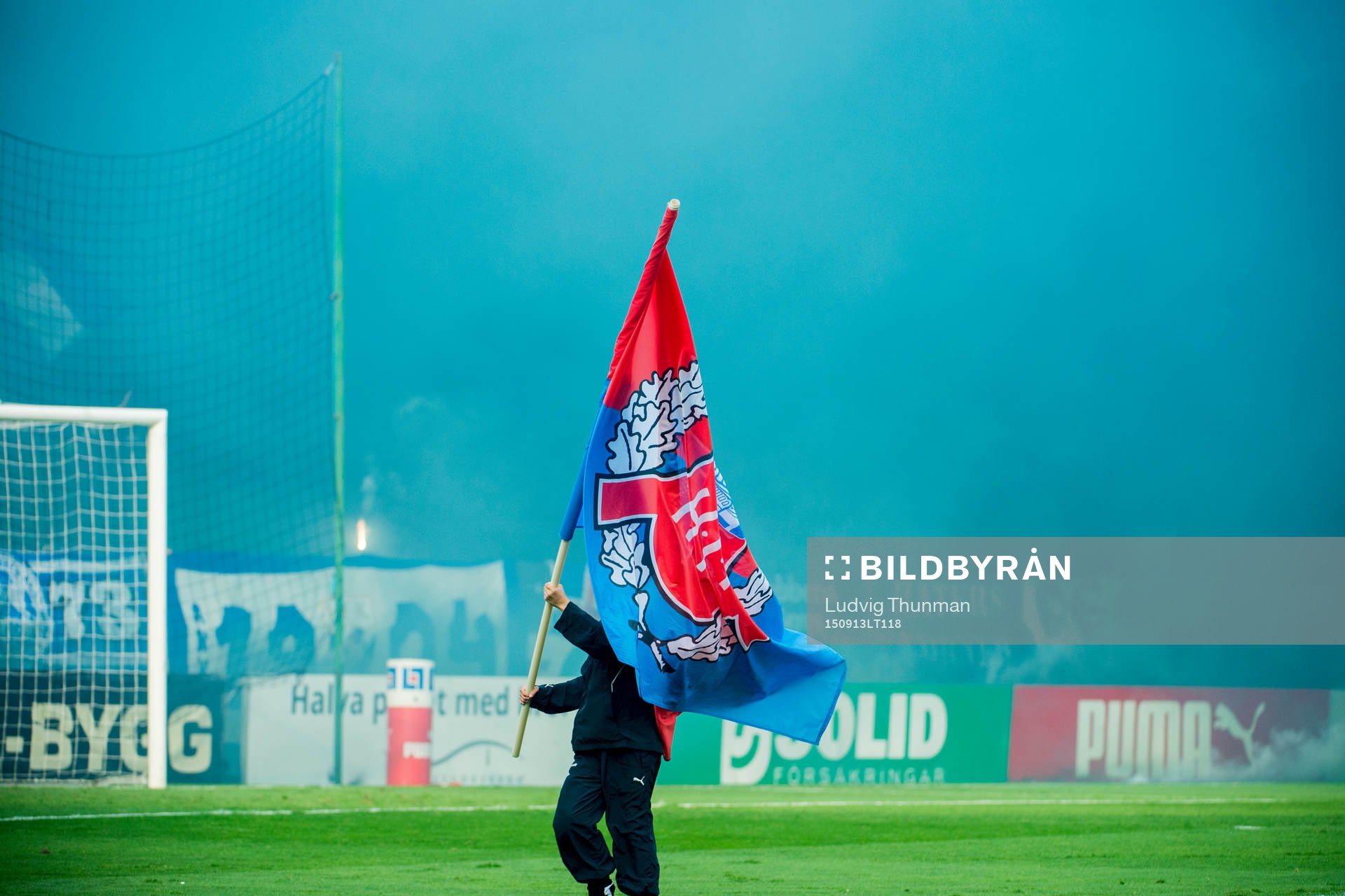 En funktionär bär en Helsingborgsflagga framför IFK