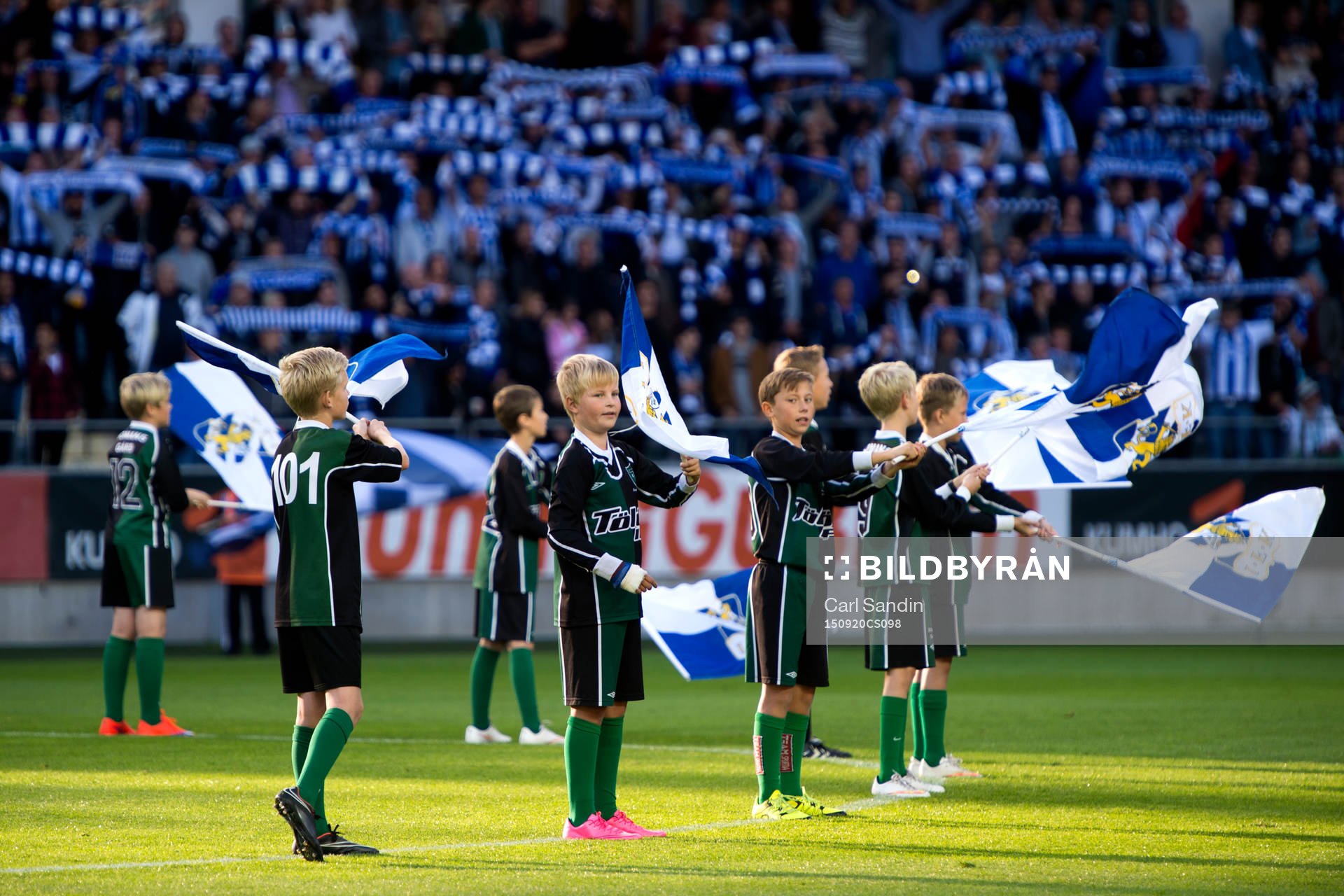 Knattar vevar med flaggor innan en fotbollsmatch i