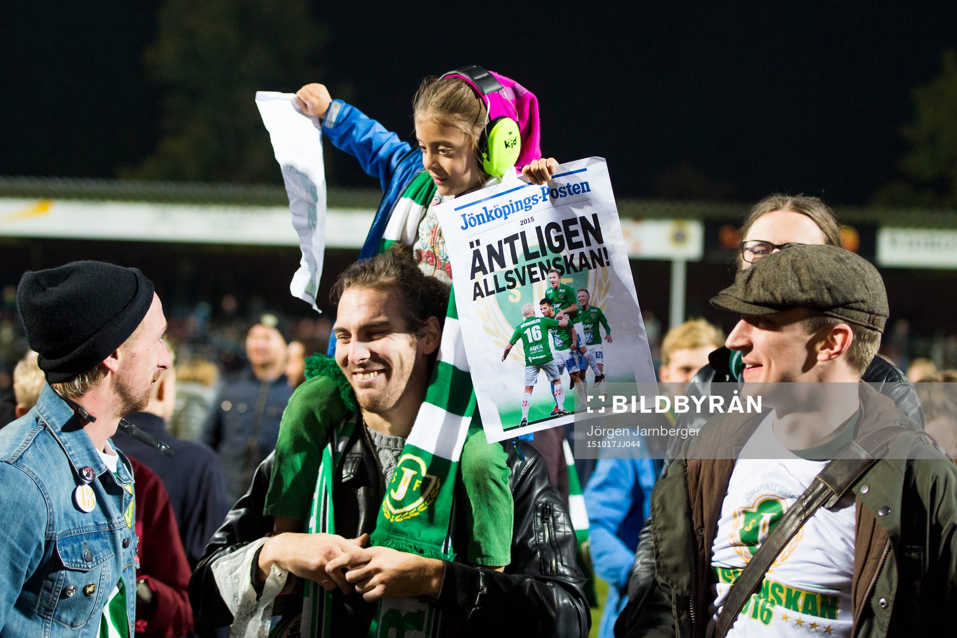 En ung supporter med hörselkåpor och löpsedlar med