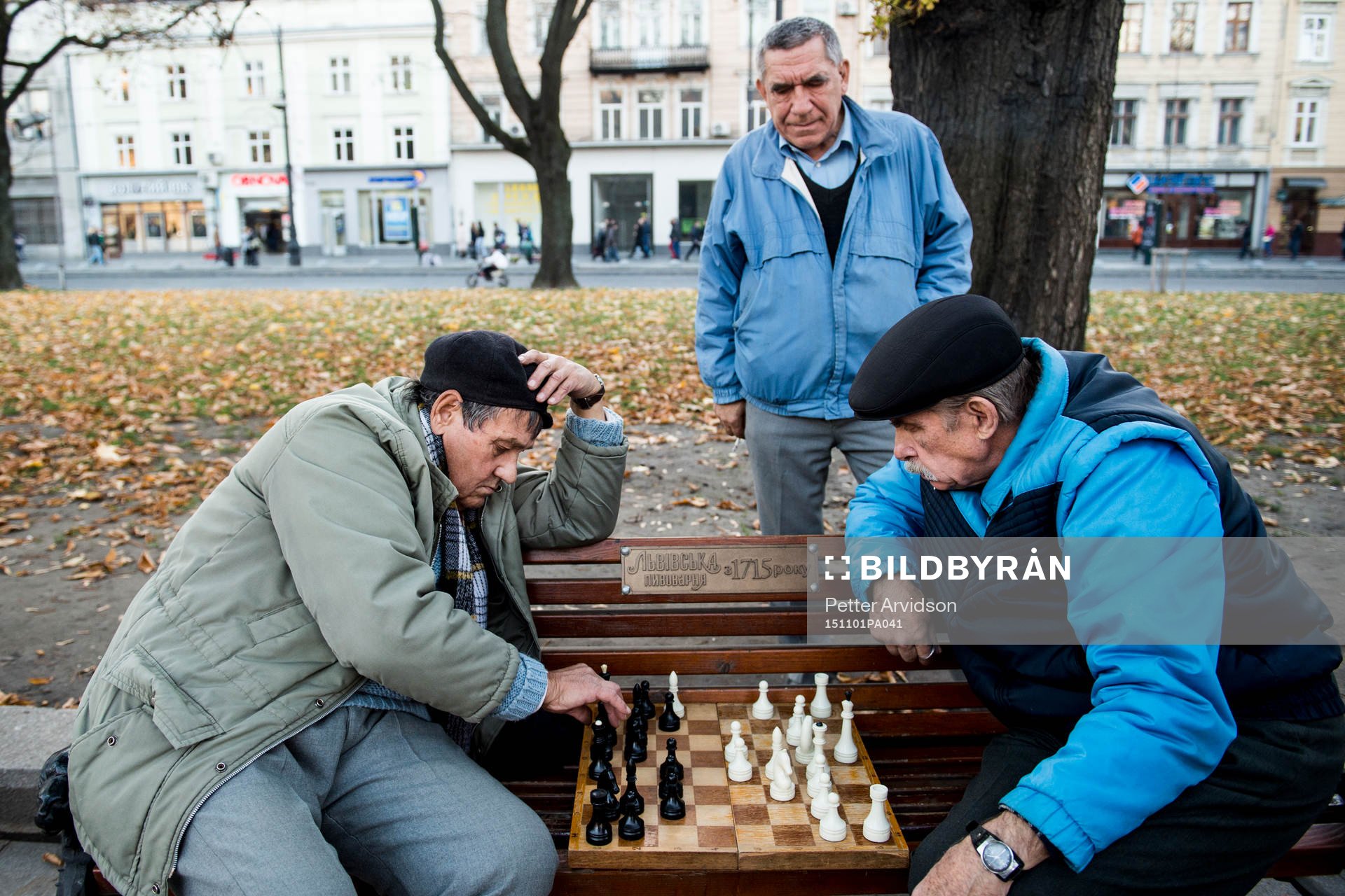 Två äldre herrar spelar schack på en parkbänk en