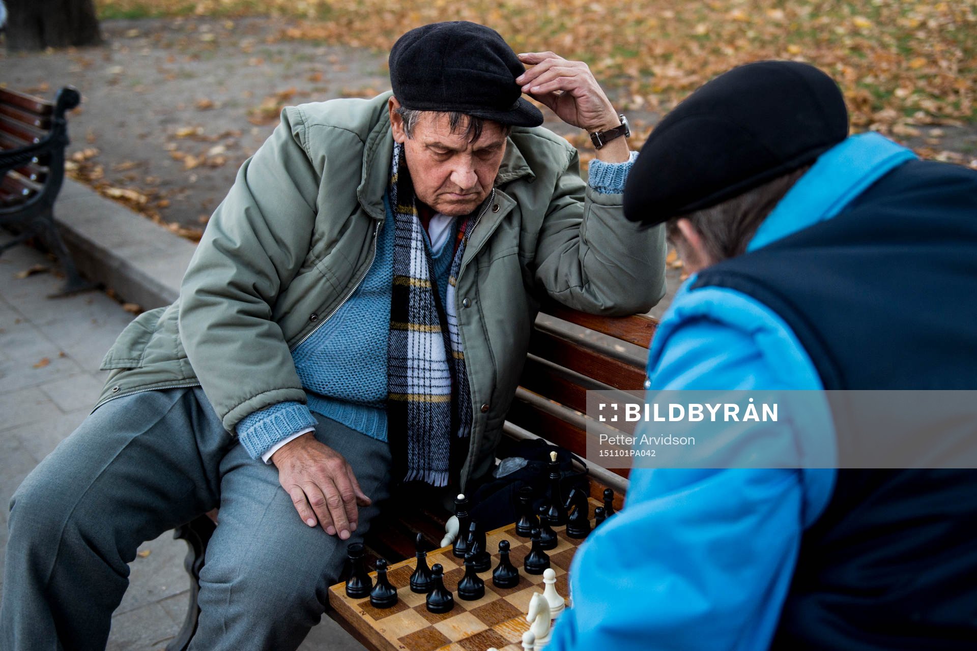 Två äldre herrar spelar schack på en parkbänk en