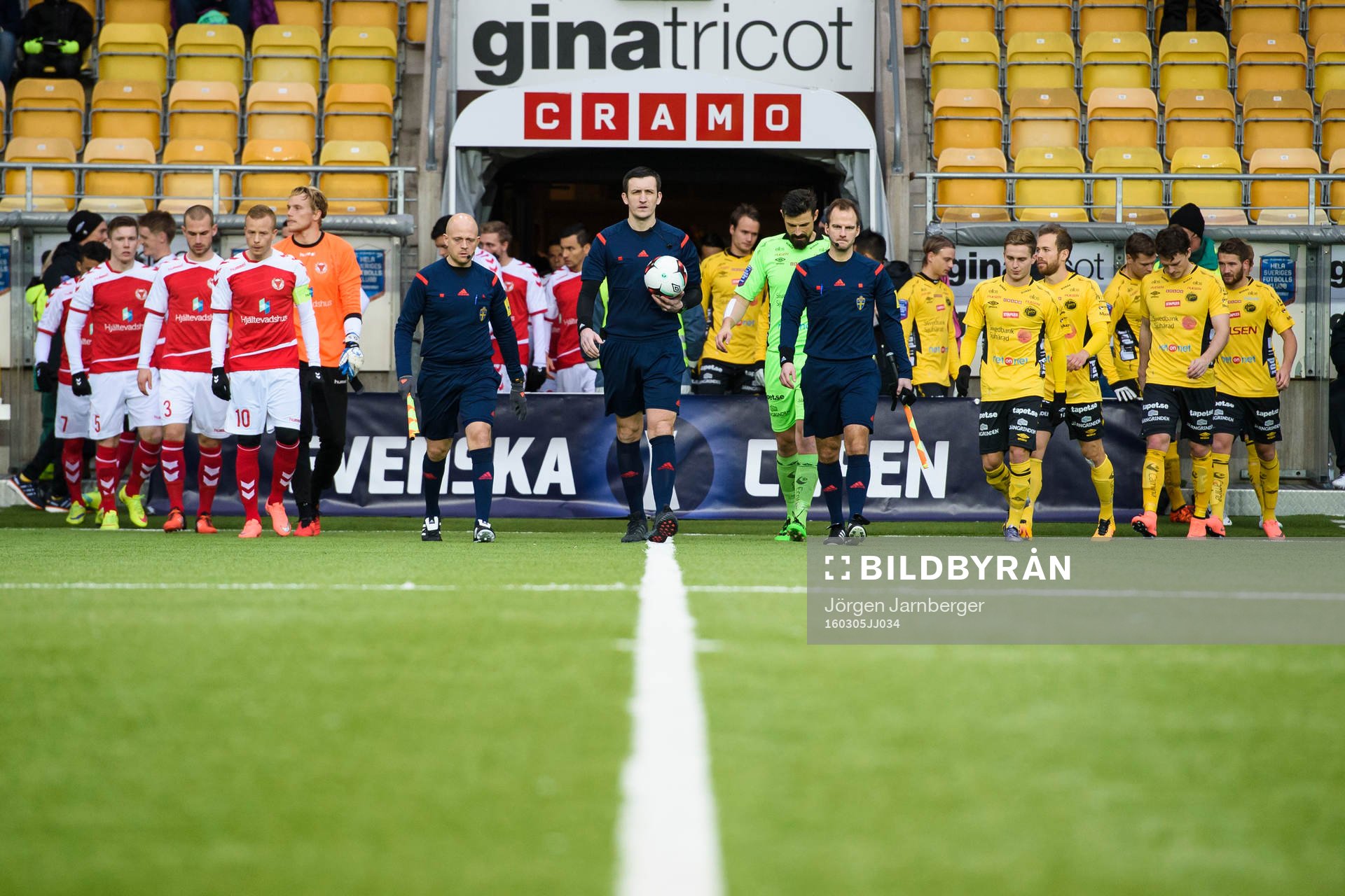 Domare och spelare kommer in till match
