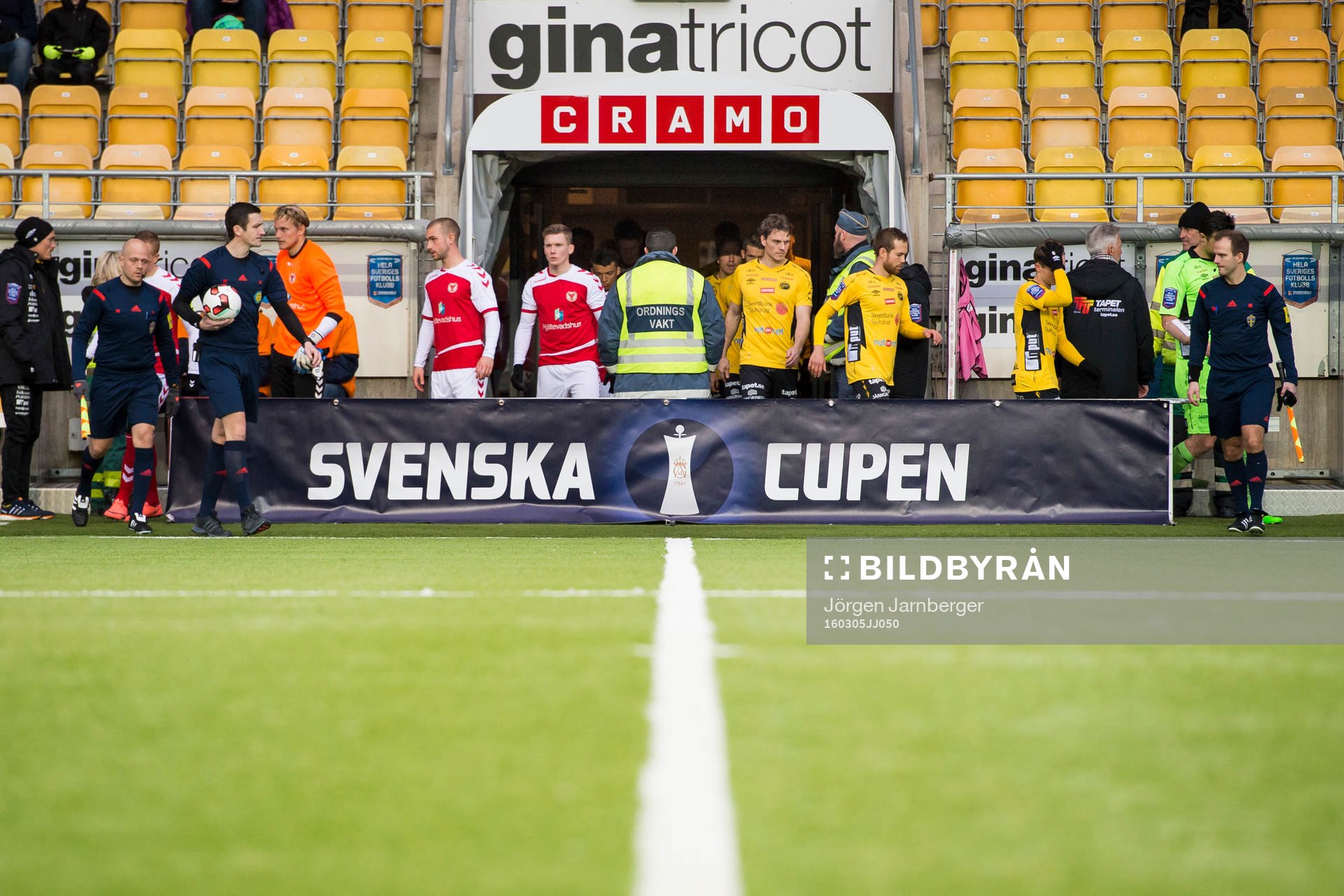 Domare och spelare kommer in på planen innan en