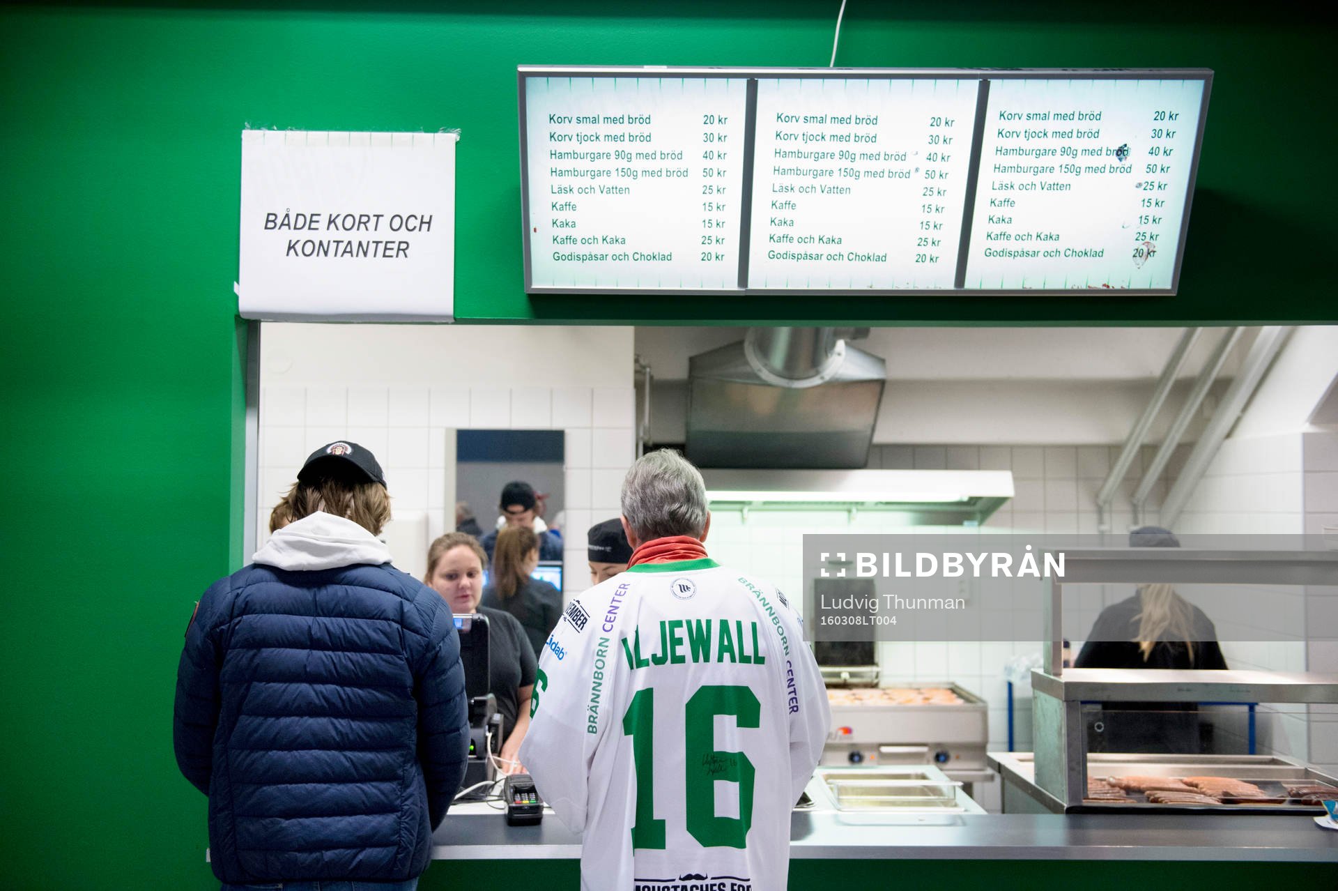 Två åskådare köar till kiosken