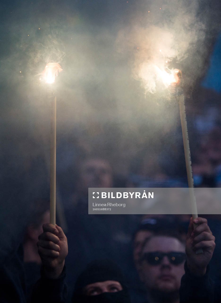En supporter i Djurgårdens klack håller upp två eldar
