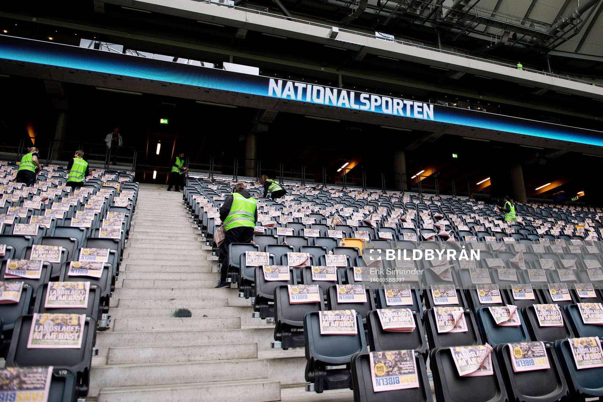 Publikvärdar placerar ut reklamblad på läktaren