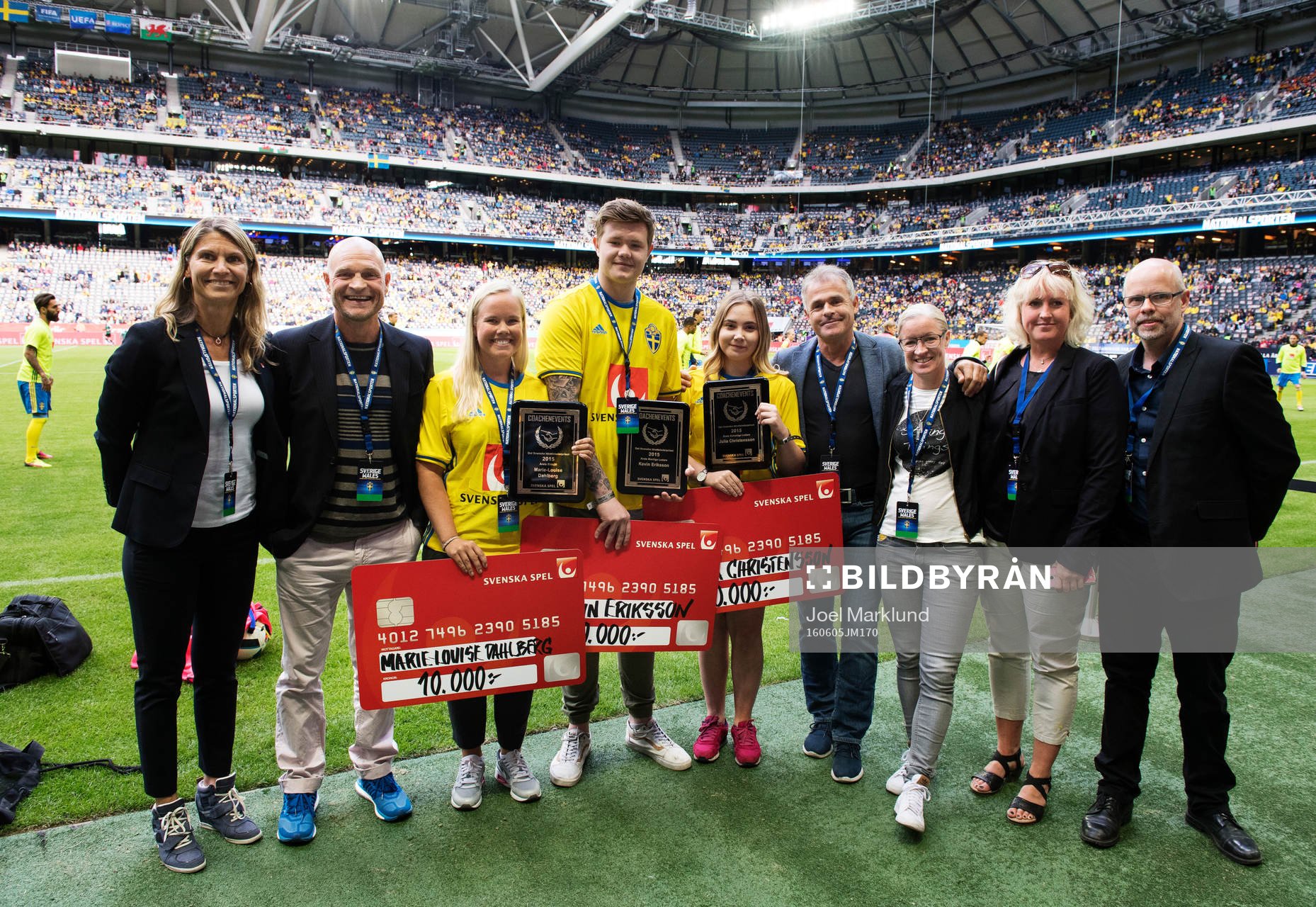 Marie-Louise Dahlberg, Kevin Eriksson och Julia Christensson poserar med pris för Det svenska idrottsledarpriset och checkar från Svenska Spel under fotbollslandskampen mellan Sverige och Wales den 5 juni 2016 i Stockholm. Vid deras sida står representanter från Svenska Spel, Pelle Fosshaug, Anders Limpar och Victoria Sandell Svensson.