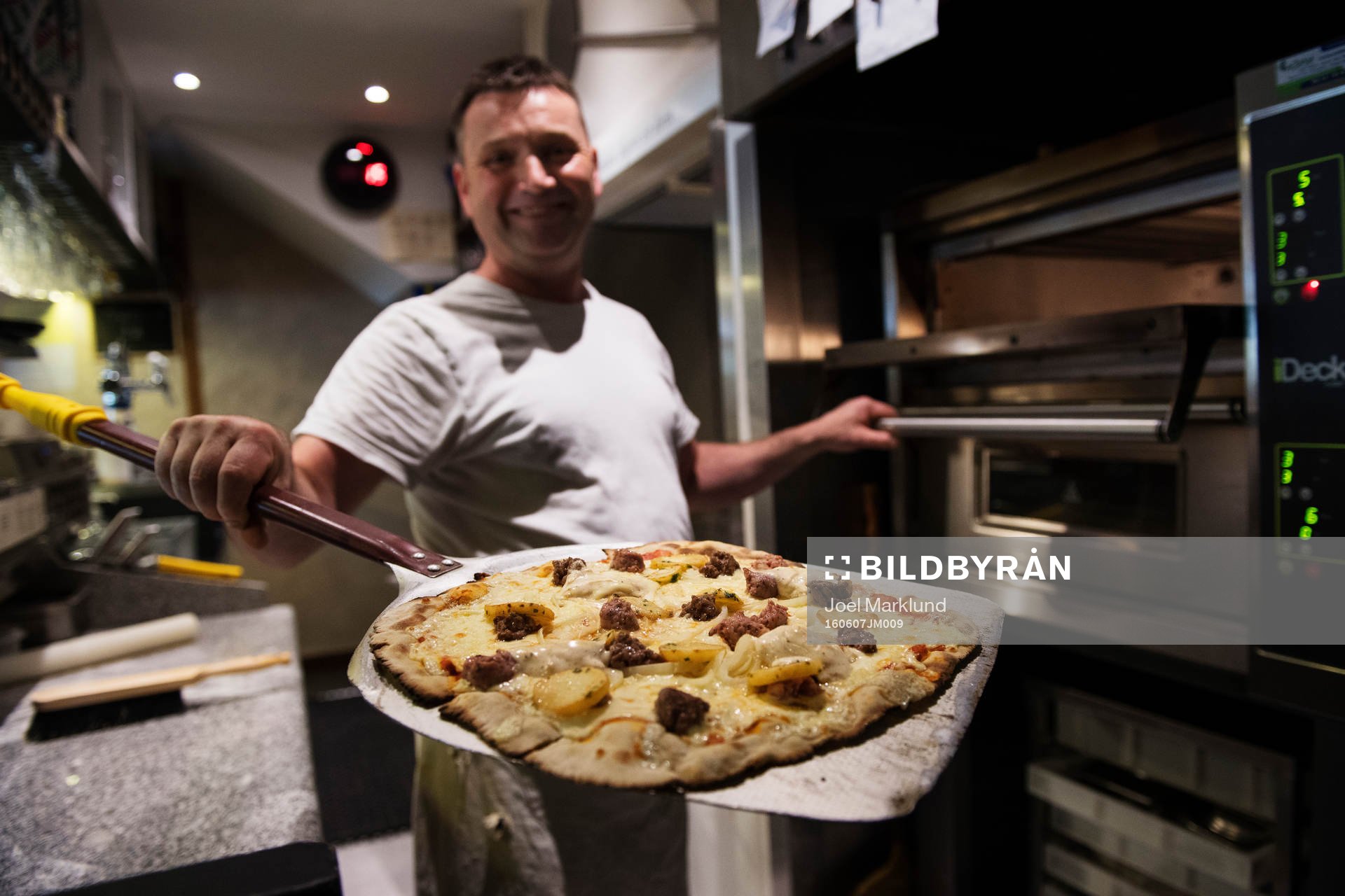 Pizzabagaren Philippe Kervella håller upp en pizza kallad