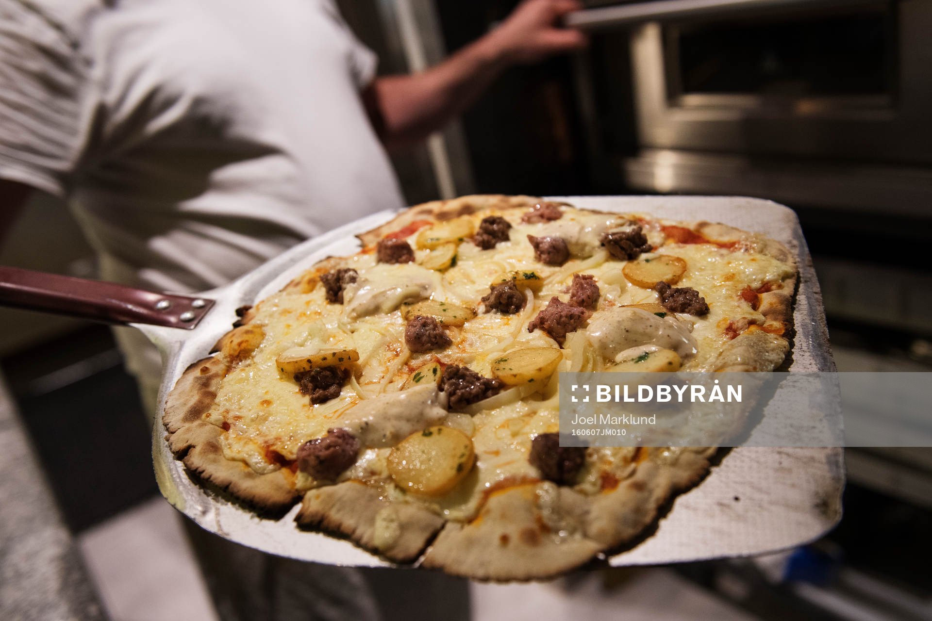 Pizzabagaren Philippe Kervella håller upp en pizza kallad