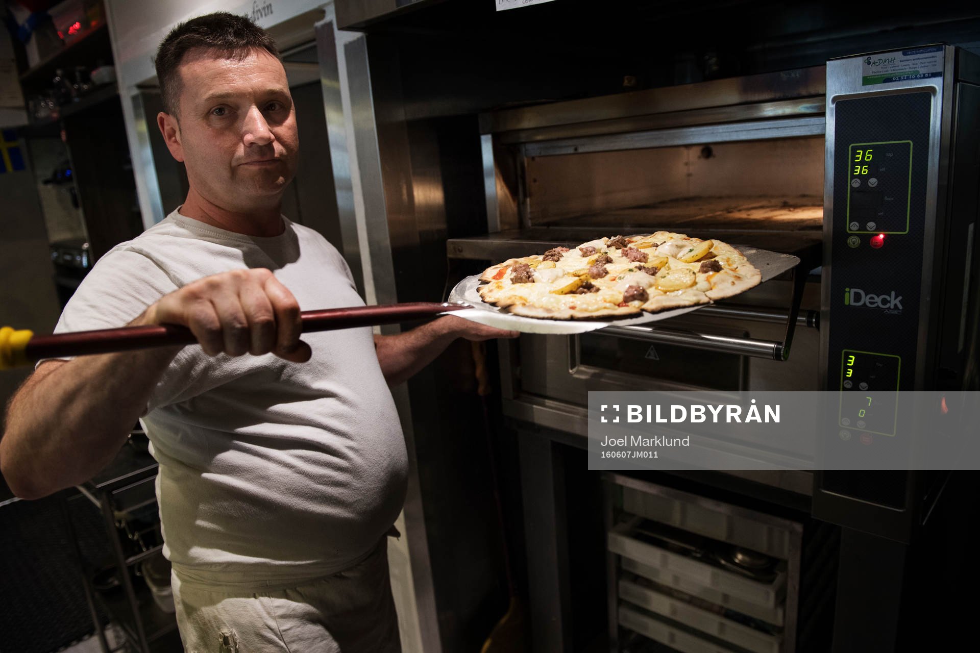 Pizzabagaren Philippe Kervella håller upp en pizza kallad