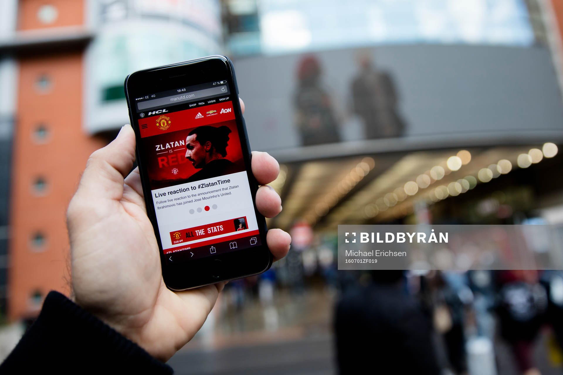 En man läser United nyheter på mobilen