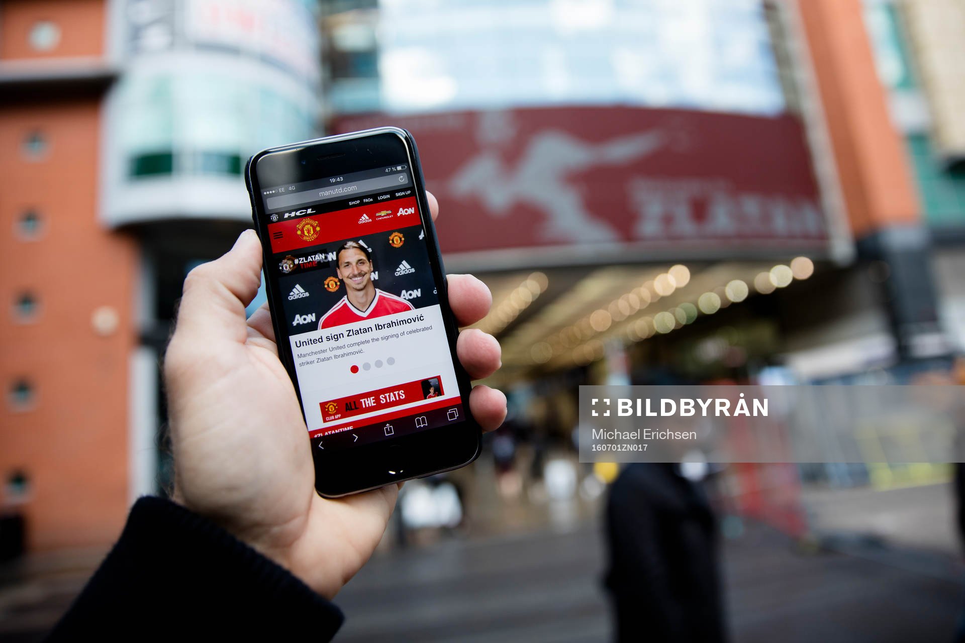En man läser United nyheter på mobilen