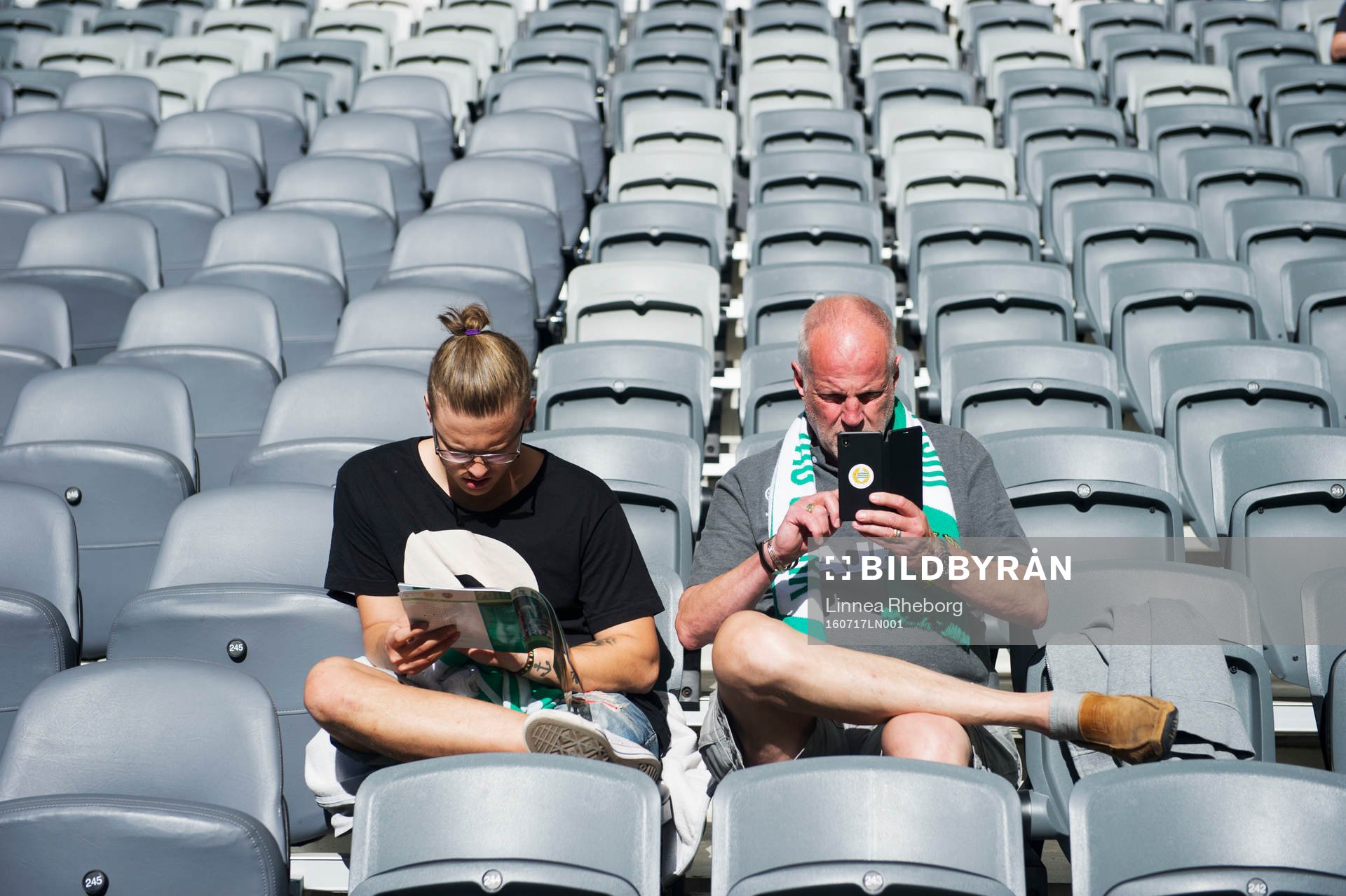Två supportrar till Hammarby sitter på läktaren
