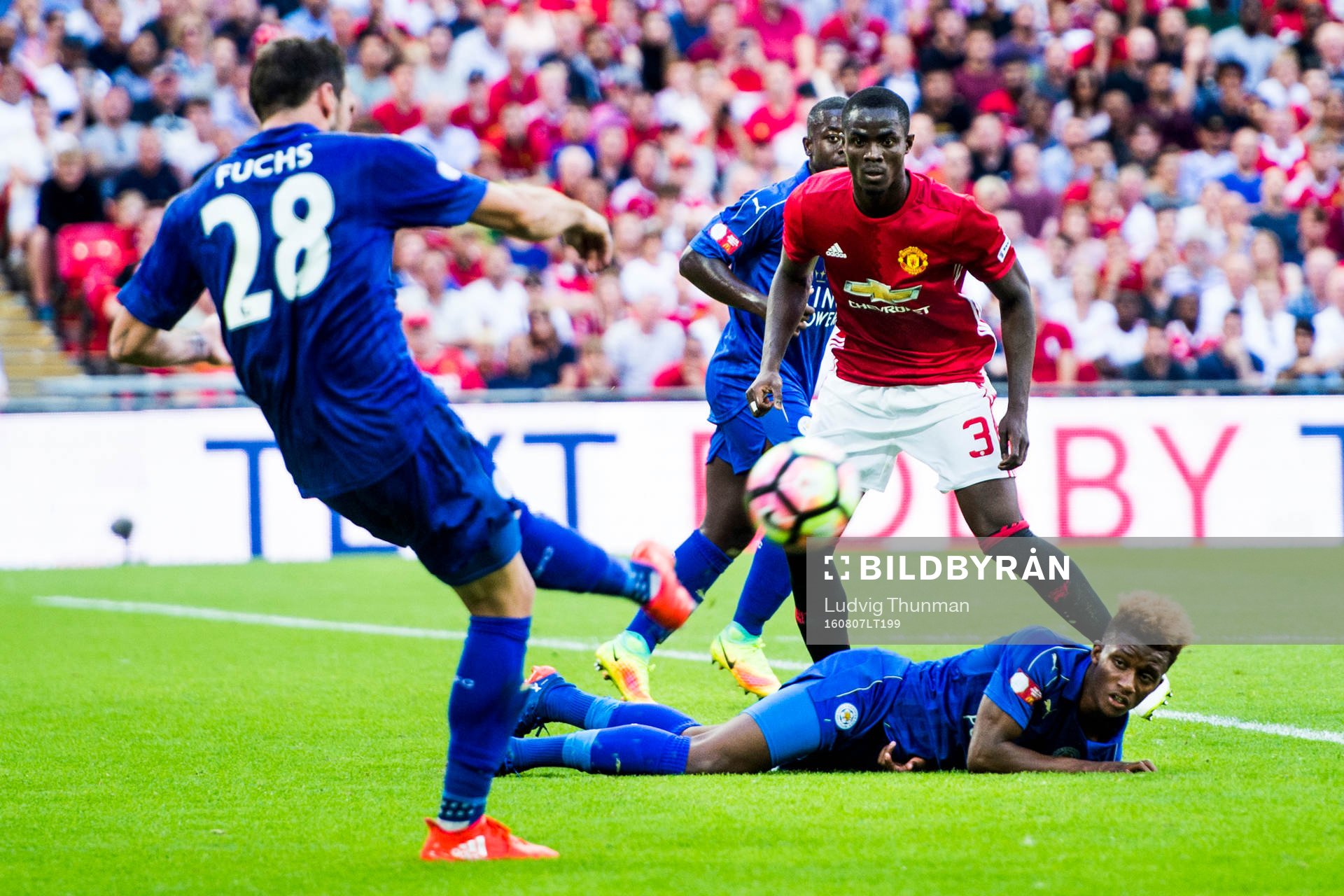 Leicester Citys Christian Fuchs rensar framför Marc Albrighton och Manchester Uniteds Eric Bailly under fotbollsmatchen Community Shield mellan Leicester City och Manchester United den 7 augusti 2016 i London.