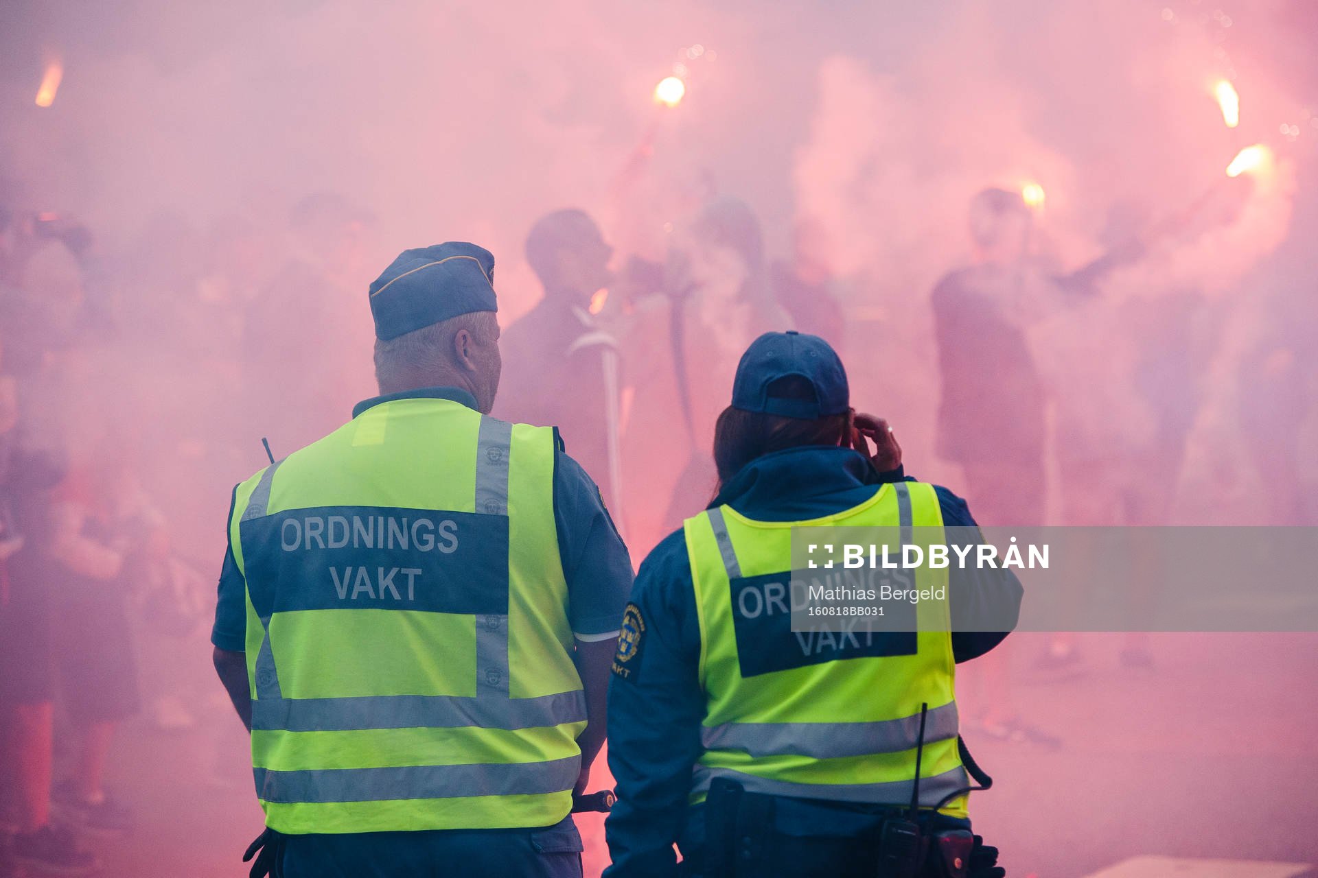 Två ordningsvakter ser IFK Göteborgs supportrar bränner