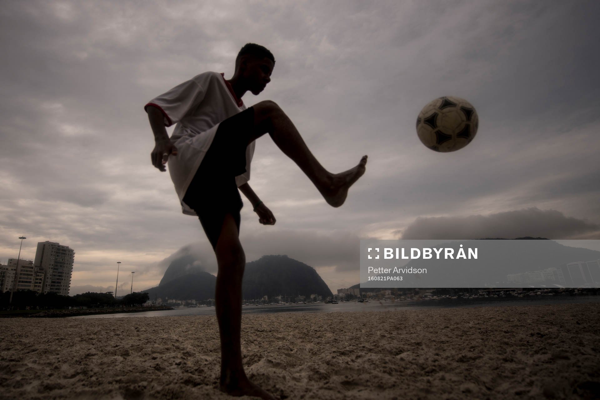 Pojke trixar med en fotboll på stranden
