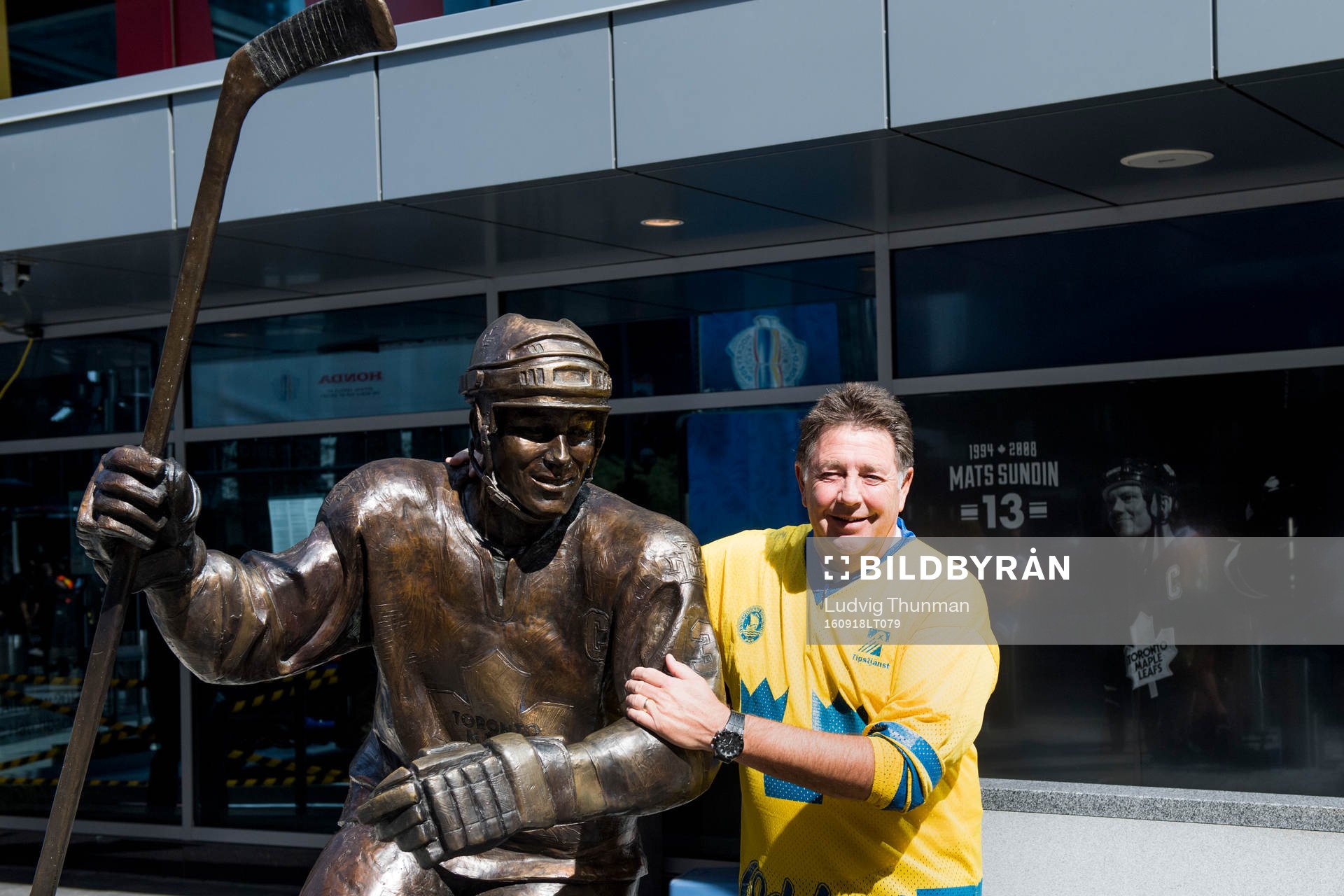 En svensk supporter blir fotograferad framför en staty av