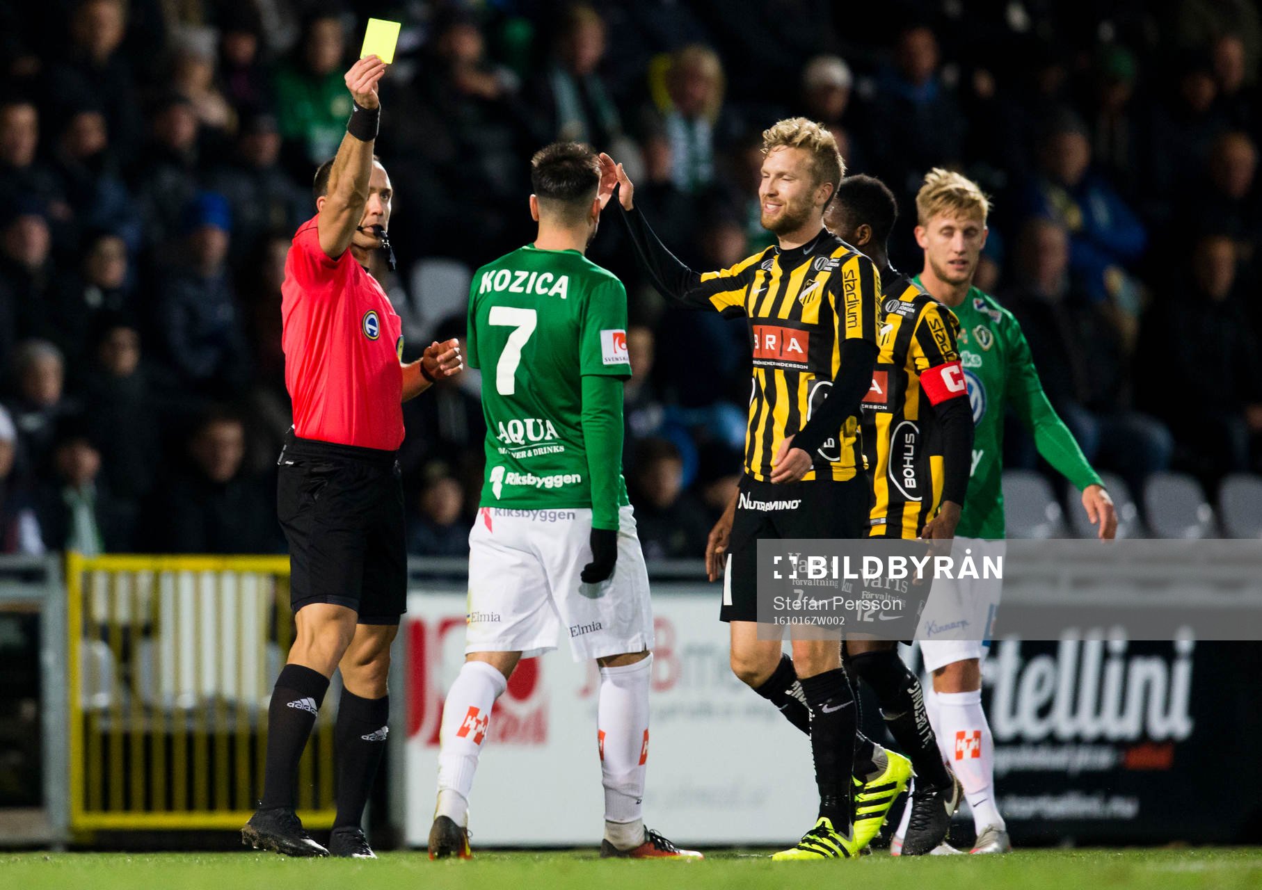 Domaren Kaspar Sjöberg delar ut ett gult kort till