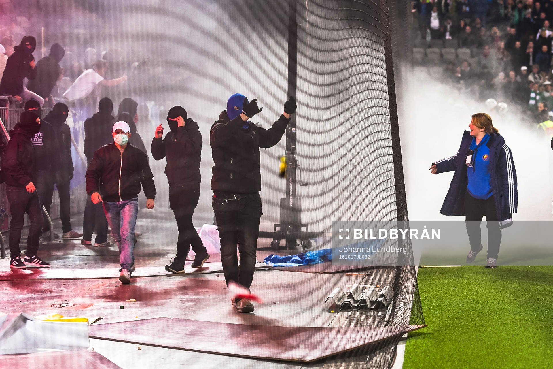 En funktionär försöker lugna ner maskerade supportrar