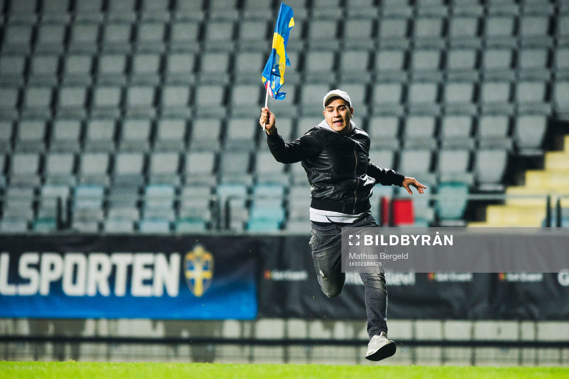 En person med svensk flagga stormar plan