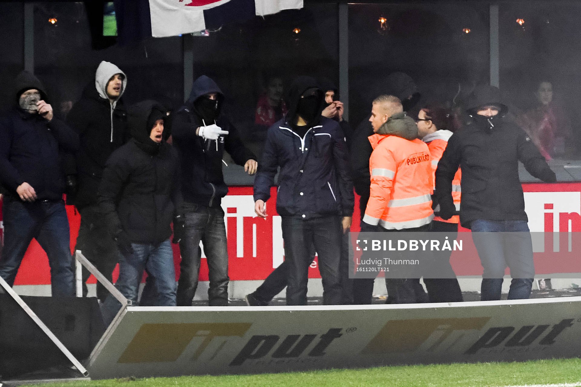 Supportar välter en reklamskylt när de stormar planen
