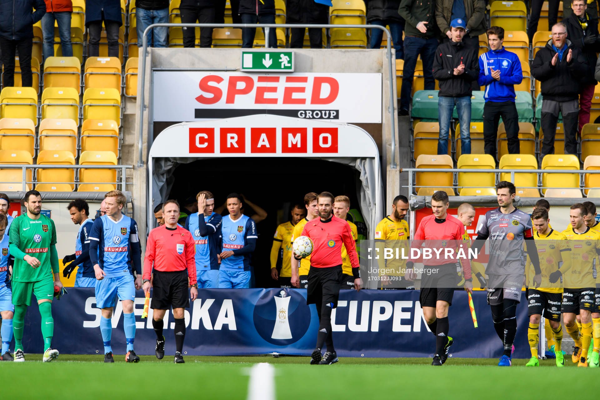 Domarna och spelarna kommer in till fotbollsmatchen i