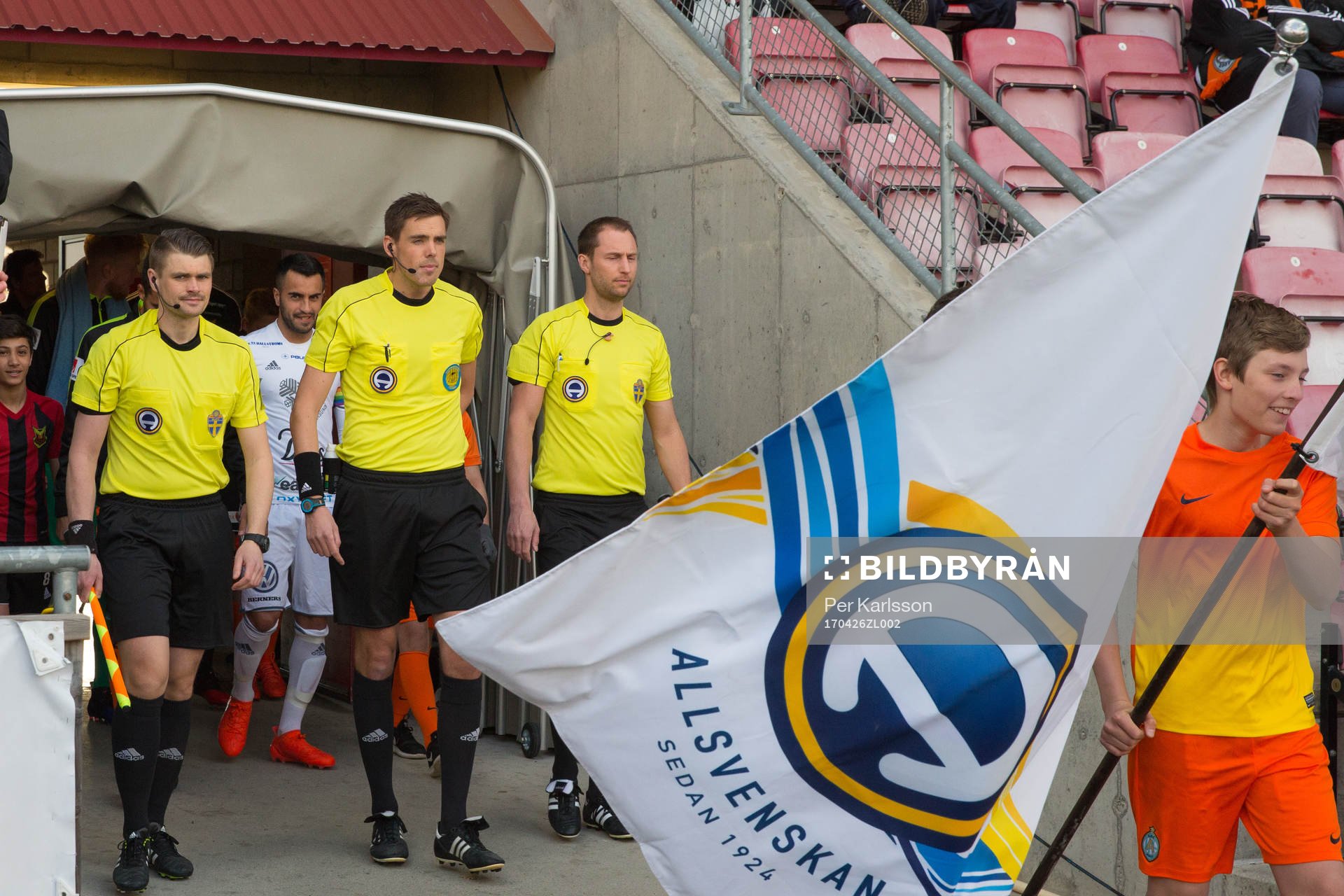 Domare och spelare går in på planen innan fotbollsmatchen