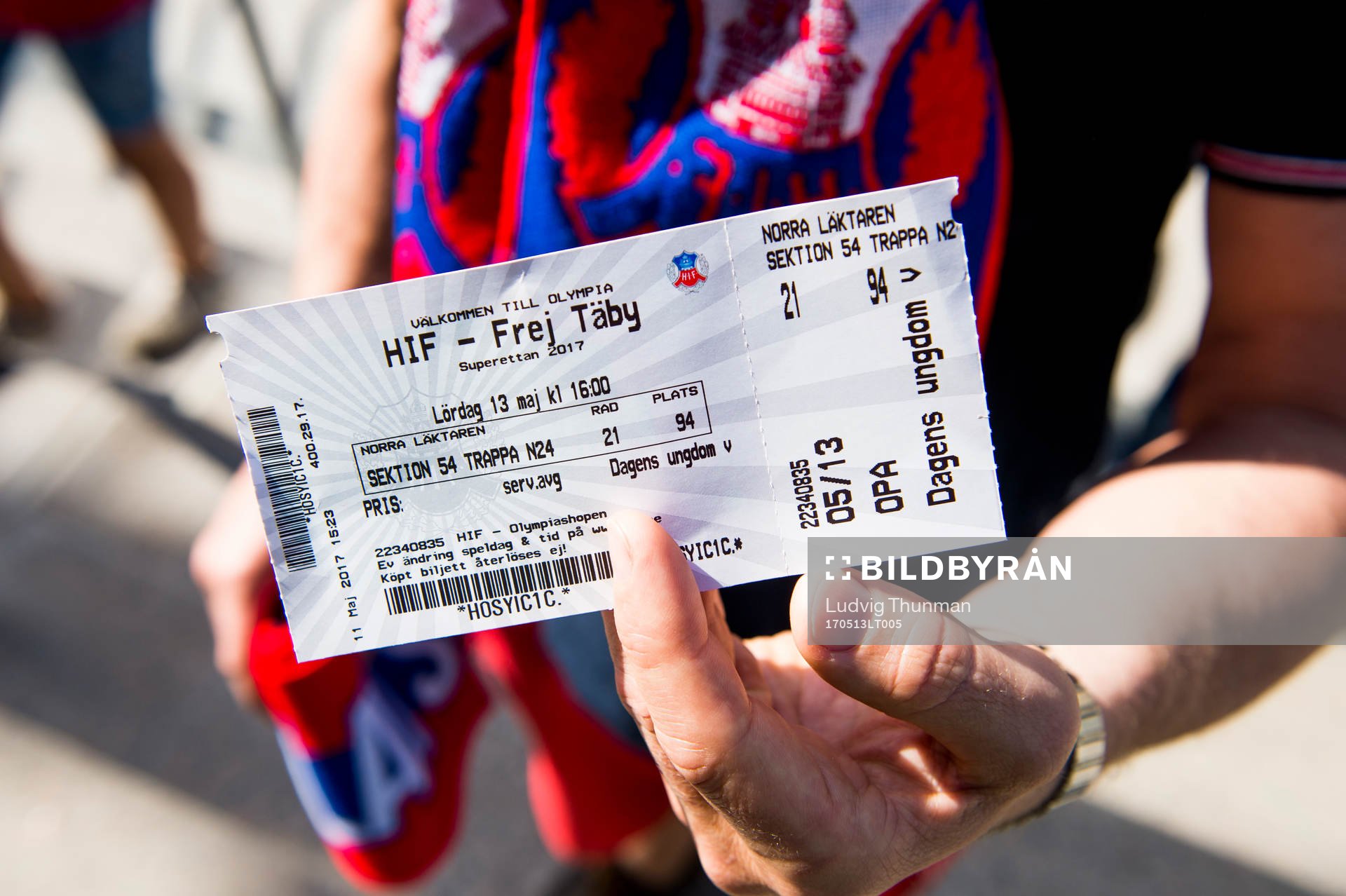 En åskådare håller upp matchbiljetten till