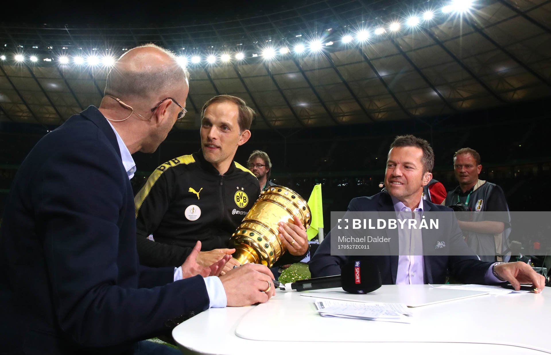 Football Soccer - Eintracht Frankfurt v Borussia Dortmund - DFB-Pokal Final - Olympic Stadium, Berlin, Germany - 27/5/17 Borussia Dortmund coach Thomas Tuchel celebrates with the trophy as he is interviewed after the match while Lothar Matthaus (R) looks on Reuters / Michael Dalder Livepic DFL RULES TO LIMIT THE ONLINE USAGE DURING MATCH TIME TO 15 PICTURES PER GAME. IMAGE SEQUENCES TO SIMULATE VIDEO IS NOT ALLOWED AT ANY TIME. FOR FURTHER QUERIES PLEASE CONTACT DFL DIRECTLY AT + 49 69 650050 DFB RULES PROHIBIT USE IN MMS SERVICES VIA HANDHELD DEVICES UNTIL TWO HOURS AFTER A MATCH AND ANY USAGE ON INTERNET OR ONLINE MEDIA SIMULATING VIDEO FOOTAGE DURING THE MATCH.