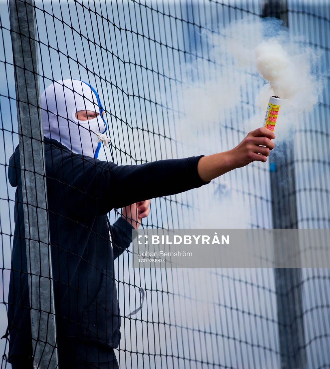 En maskerad Norrköpingssupporter med pyroteknik