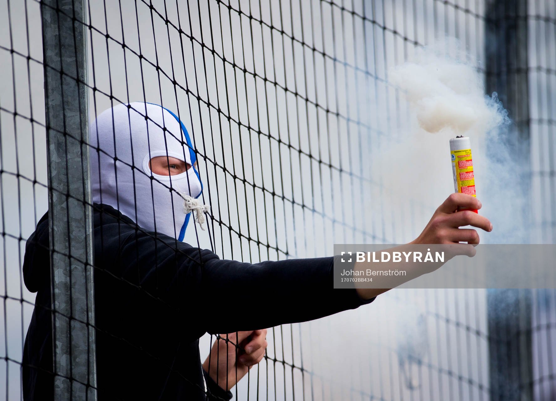 En maskerad Norrköpingssupporter med pyroteknik