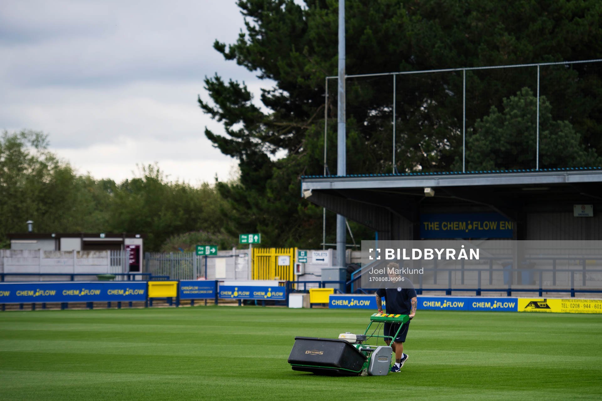 En planskötare klipper gräs på fotbollsplanen för